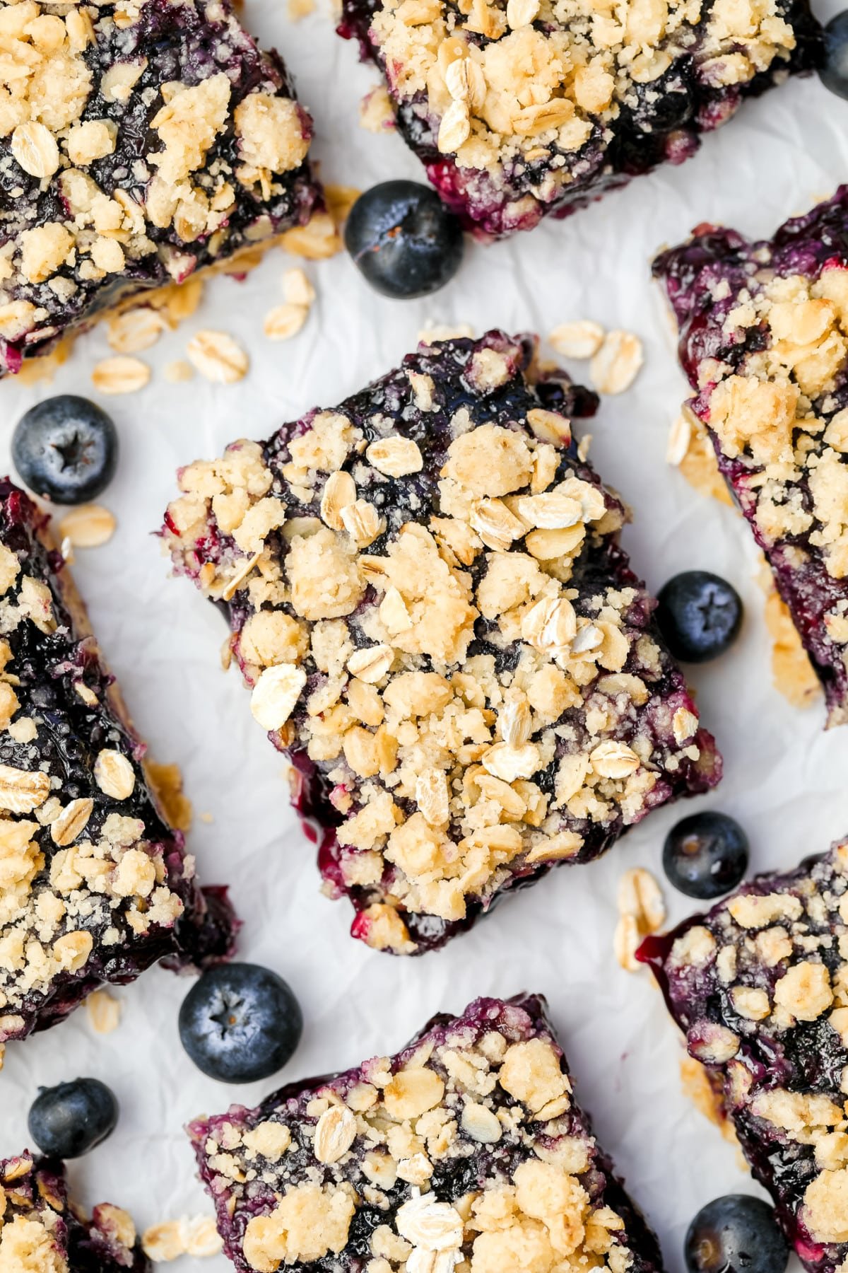 looking down on pie bars with crumb topping, white background and with blueberries around them