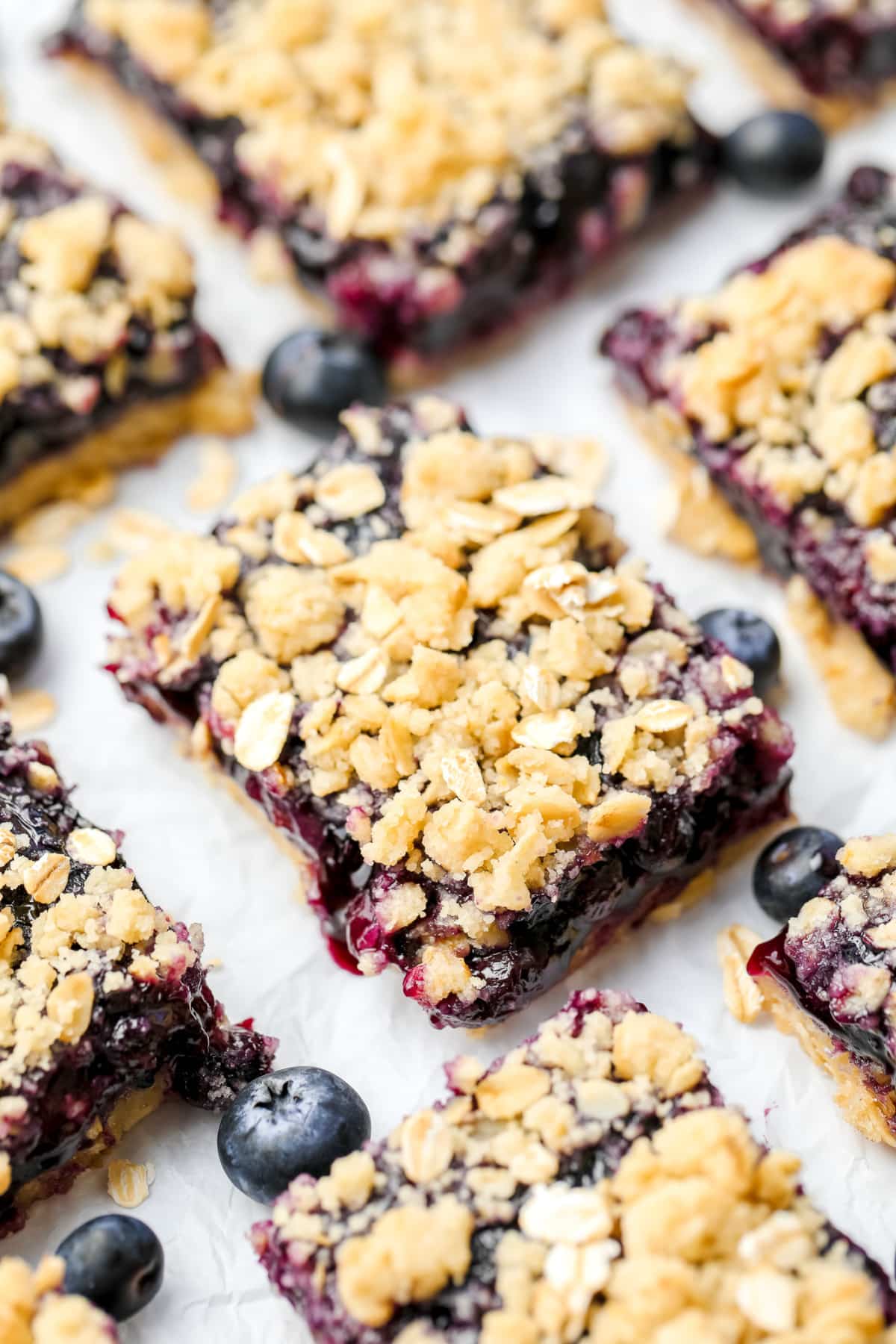 many fruit bars with blueberries and crumb topping on white background in a row