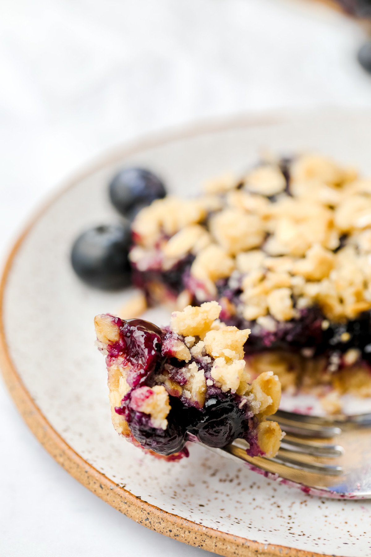 a bite of bar on a fork showing cooked blueberry mixture and crumb topping