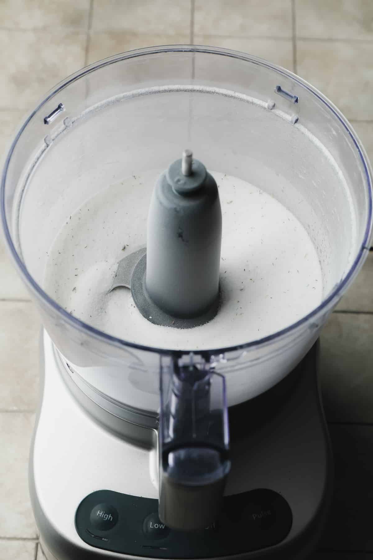 food processor with sugar and little specks of lavender on grey background