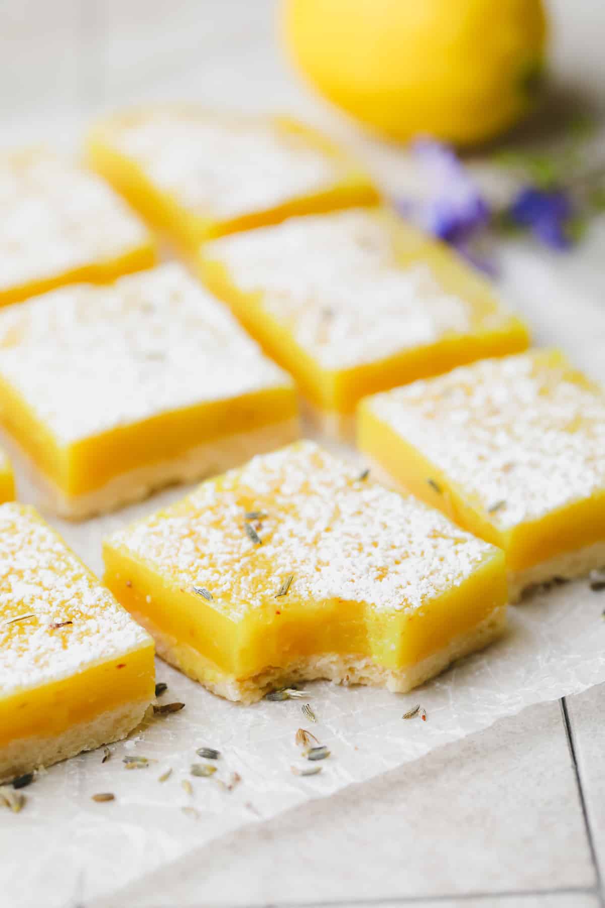 Take a bite from a lemon bar, back it on parchment paper with lavender flakes.