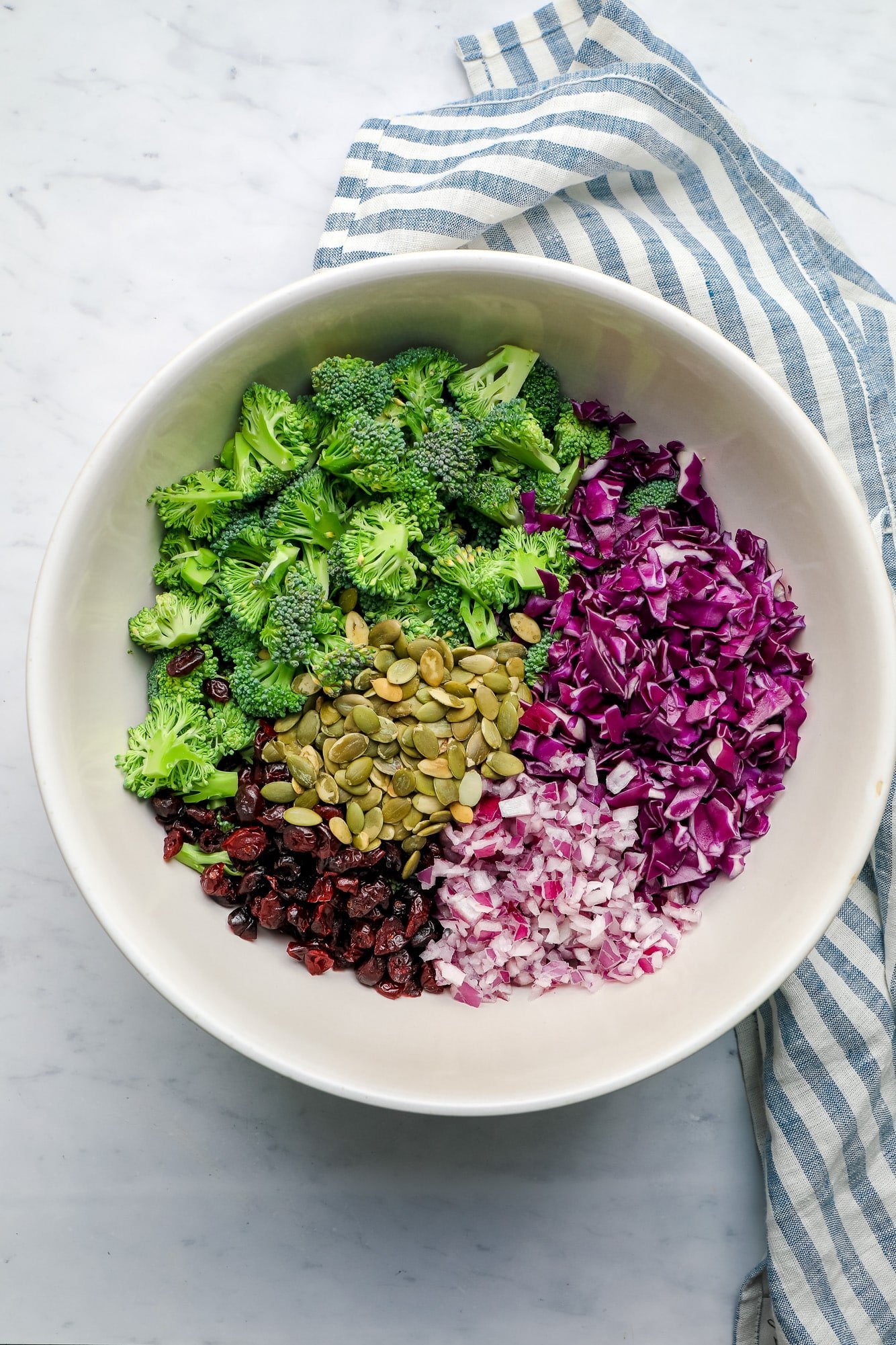 Zutaten für veganen Brokkolisalat zusammen in einer großen weißen Schüssel servieren.
