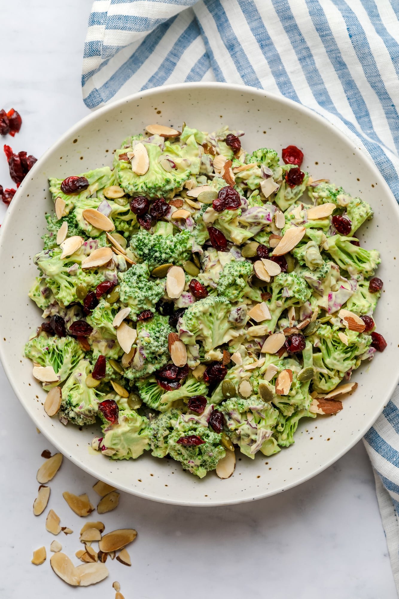 vegan broccoli salad tossed in creamy dressing and topped with almonds in a large white bowl.