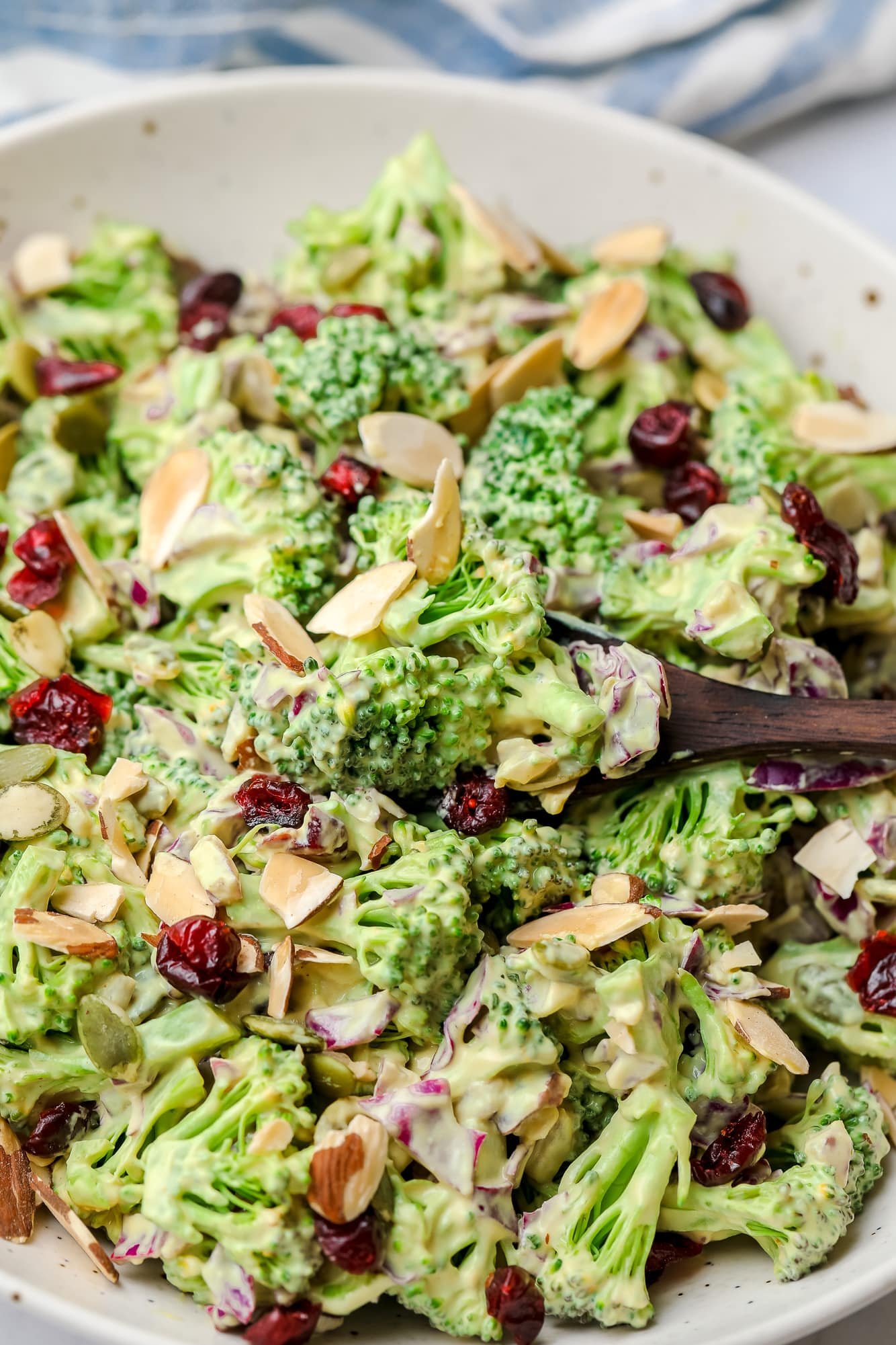 using a wood spoon to scoop up a bite of vegan broccoli salad.