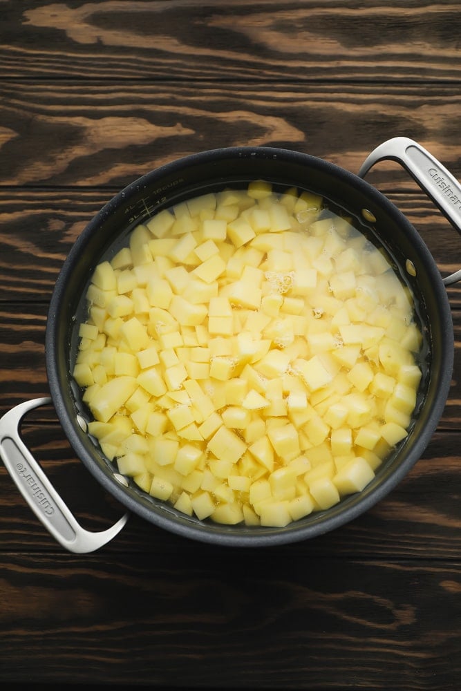 black pot full of yellow potatoes on wood background