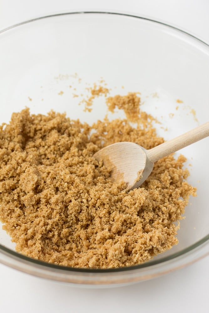 golden crumbs with a spoon in a glass bowl on white background