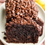 a sliced loaf of vegan chocolate banana bread on a white plate.