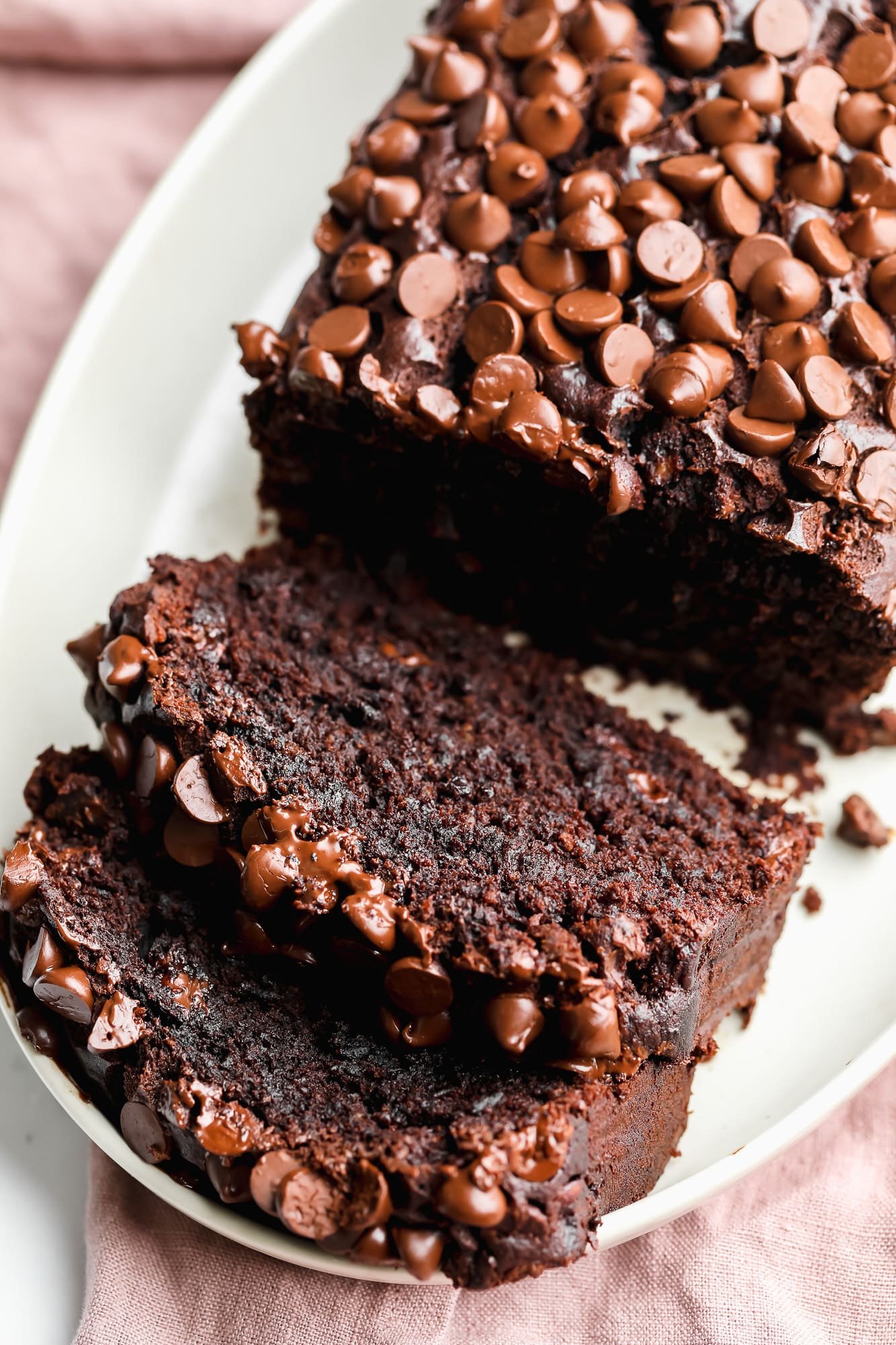 a sliced loaf of vegan chocolate banana bread on a white plate.