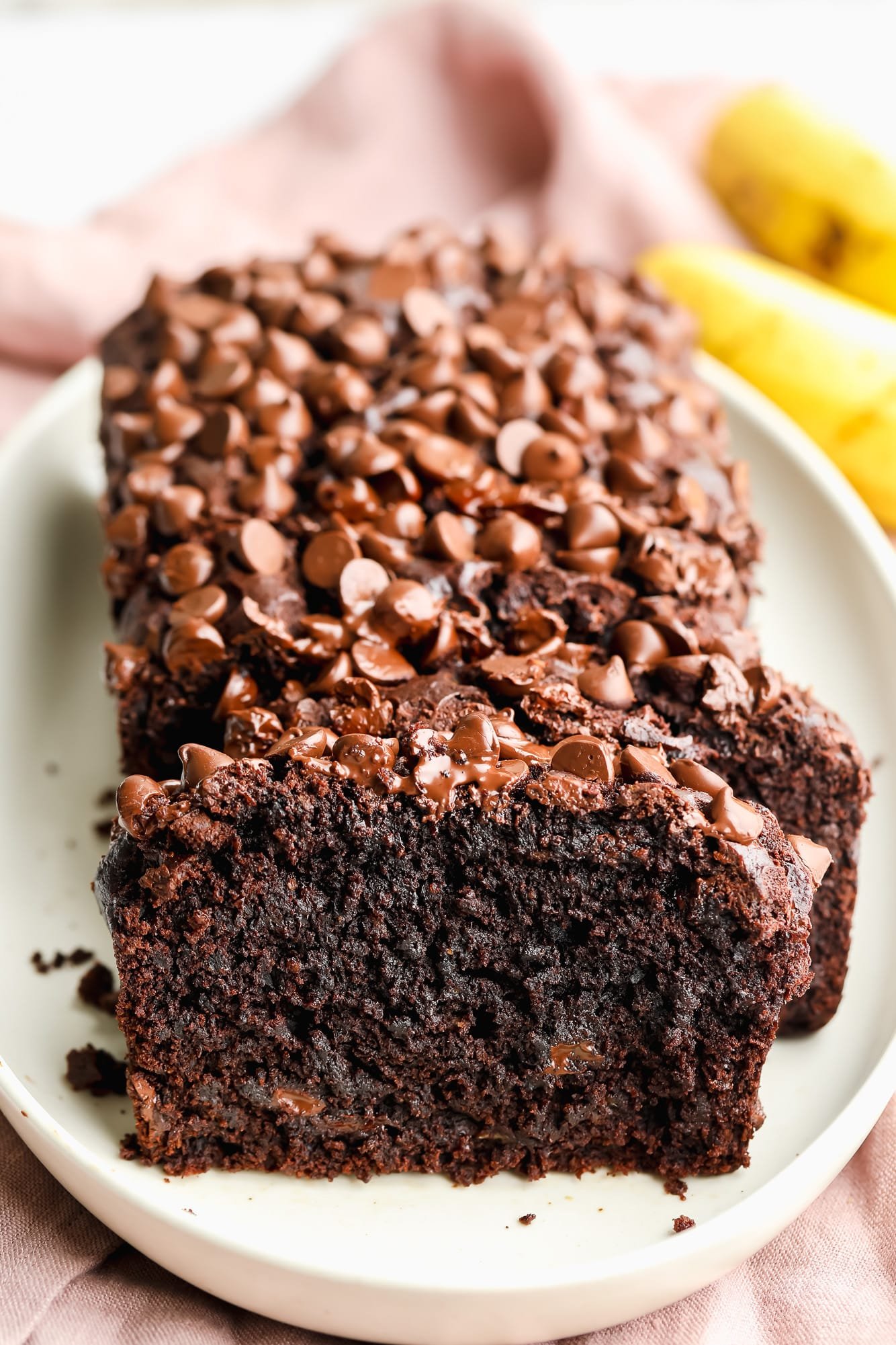 a sliced loaf of vegan chocolate banana bread on a white plate.