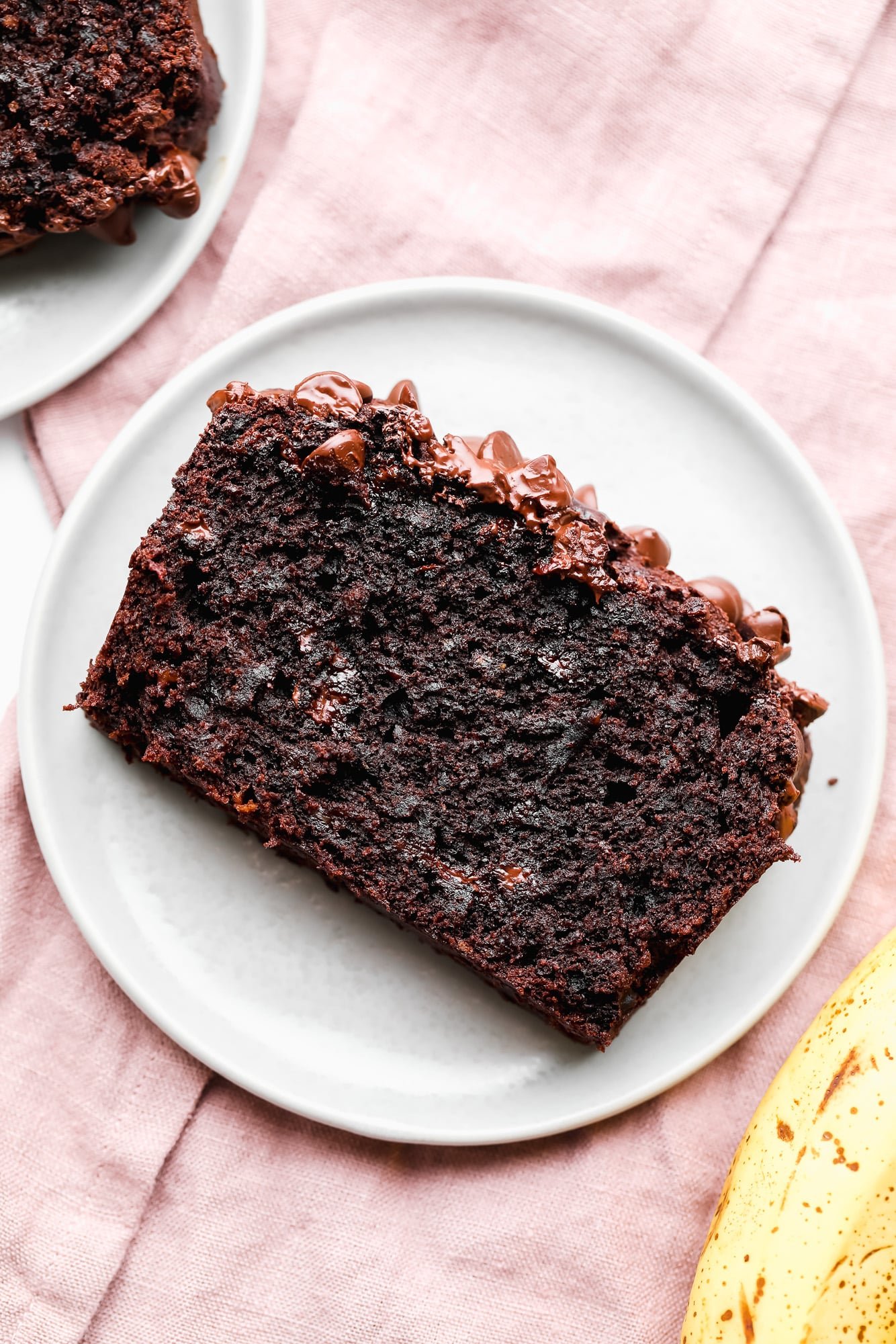 a slice of vegan chocolate banana bread on a white plate.