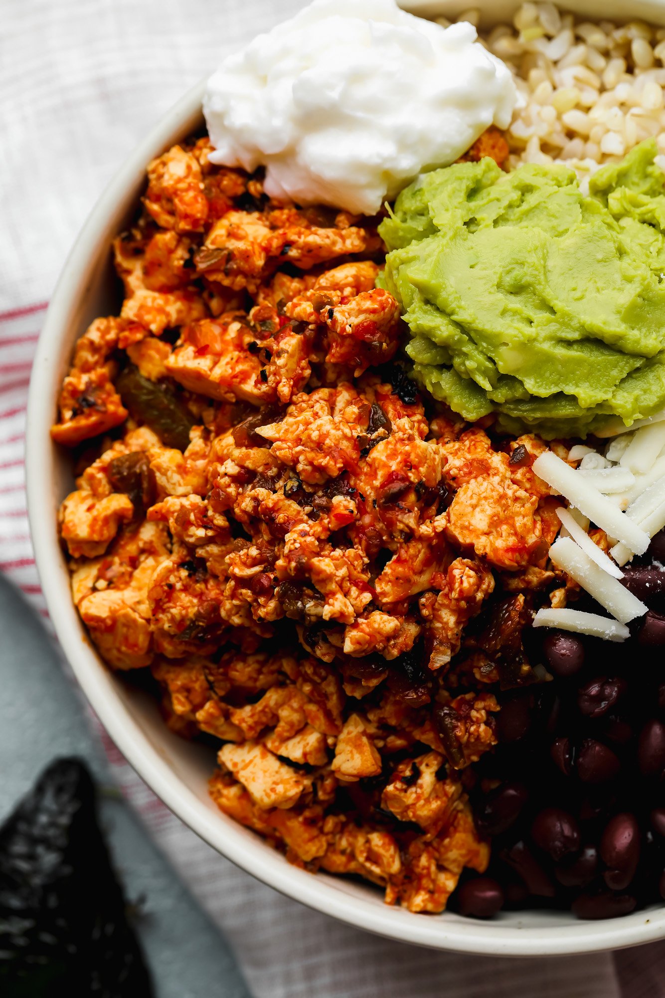 a vegan burrito bowl topped with sofritas, black beans, shredded cheese, and guacamole.