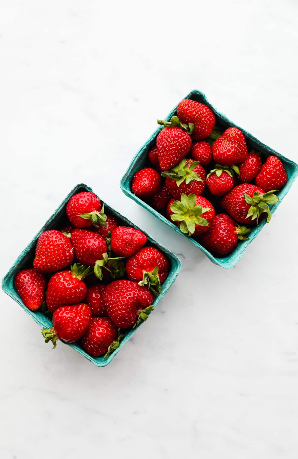 2 blue baskets filled with fresh strawberries.