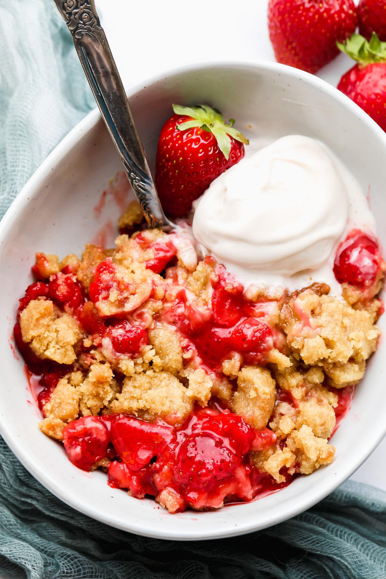 strawberry crumble in a white bowl with a scoop of vanilla ice cream.