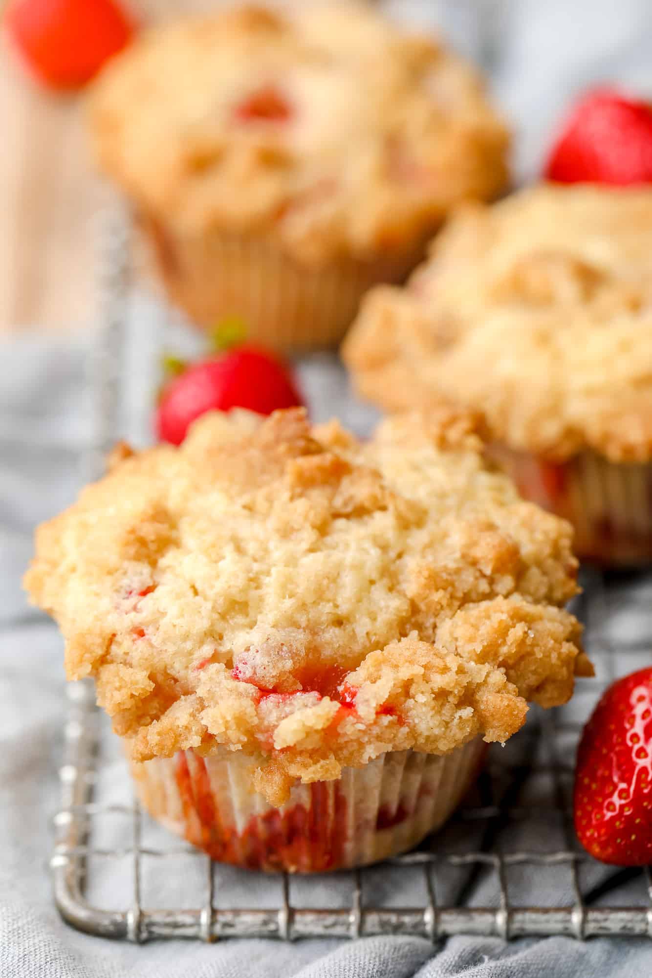 close up on a baked vegan strawberry muffin on a wire rack.