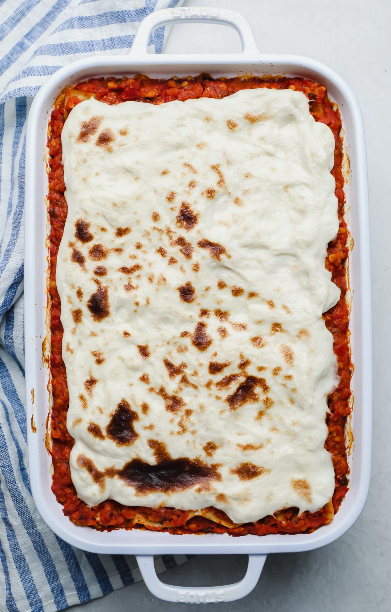 casserole topped with vegan mozzarella cheese in a white casserole dish.