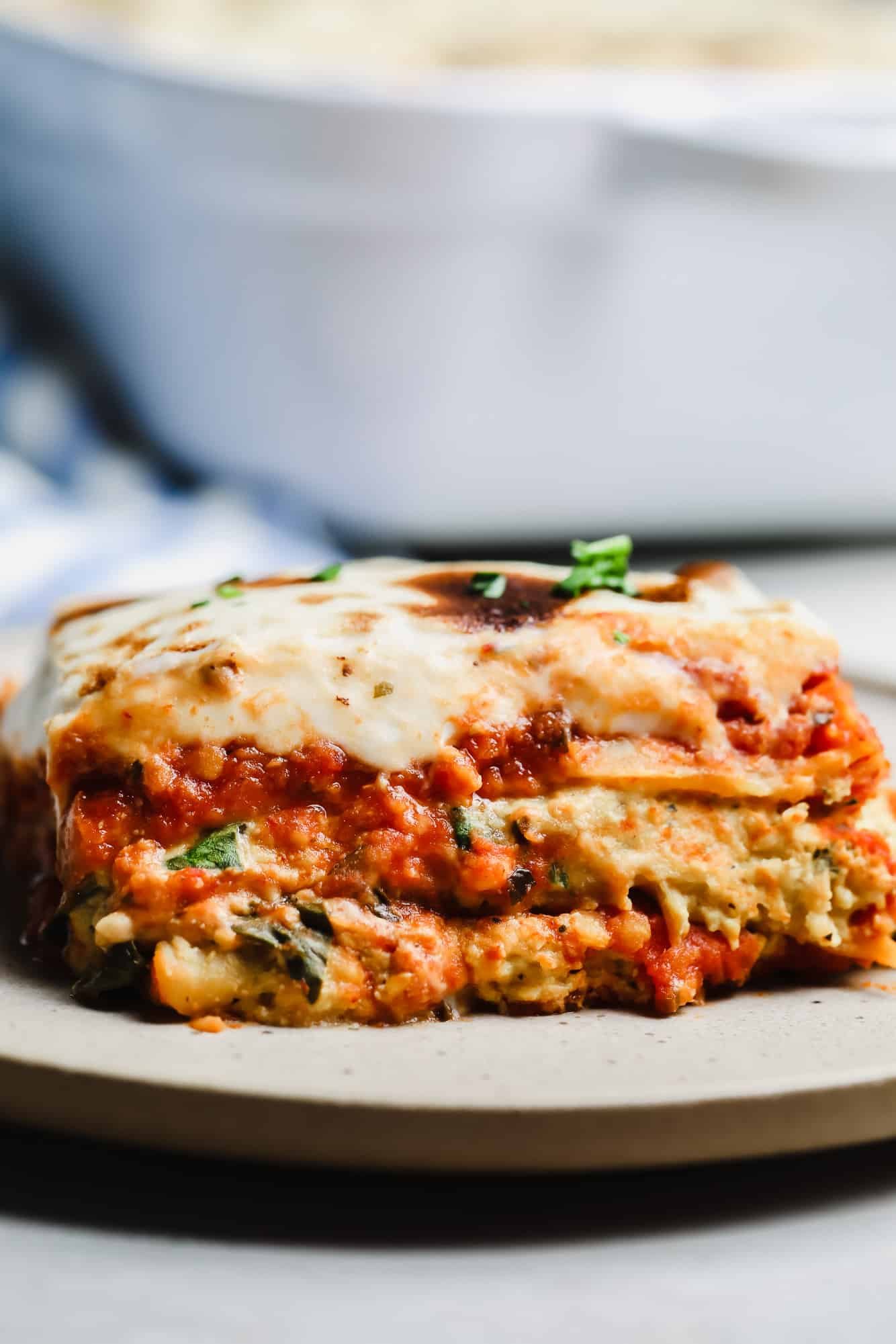 close up on a slice of vegan lasagna on a white plate.