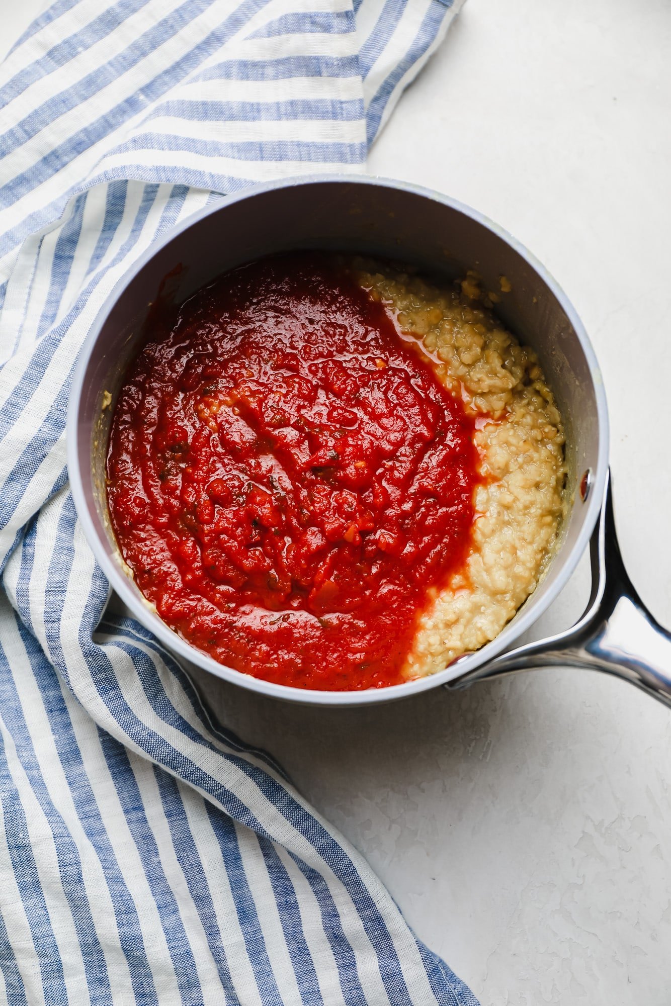 marinara sauce and cooked red lentils in a white saucepan.