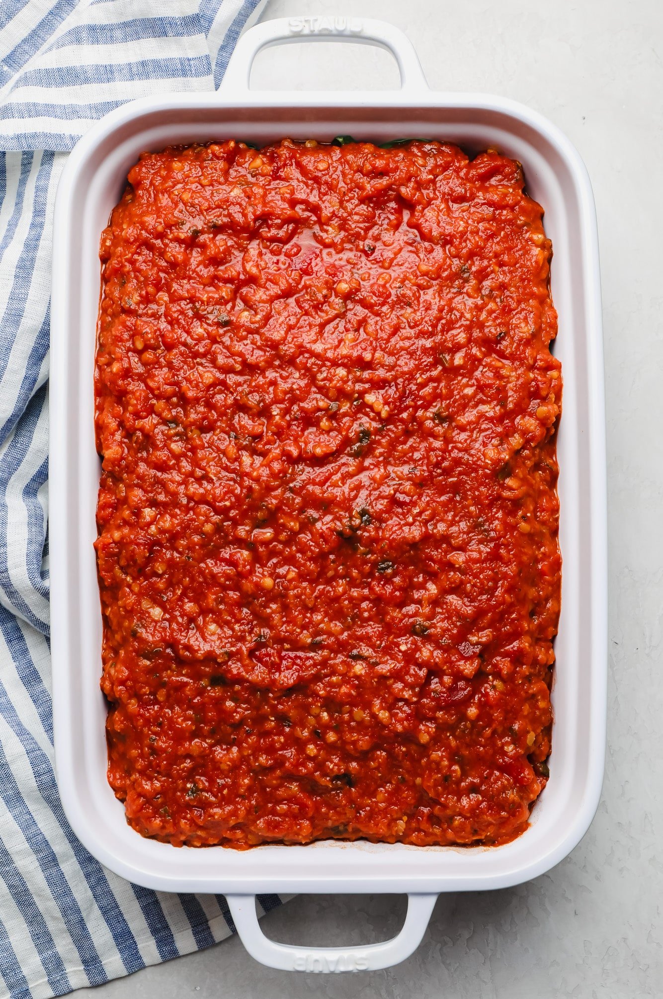 layering spinach and red sauce in a casserole dish