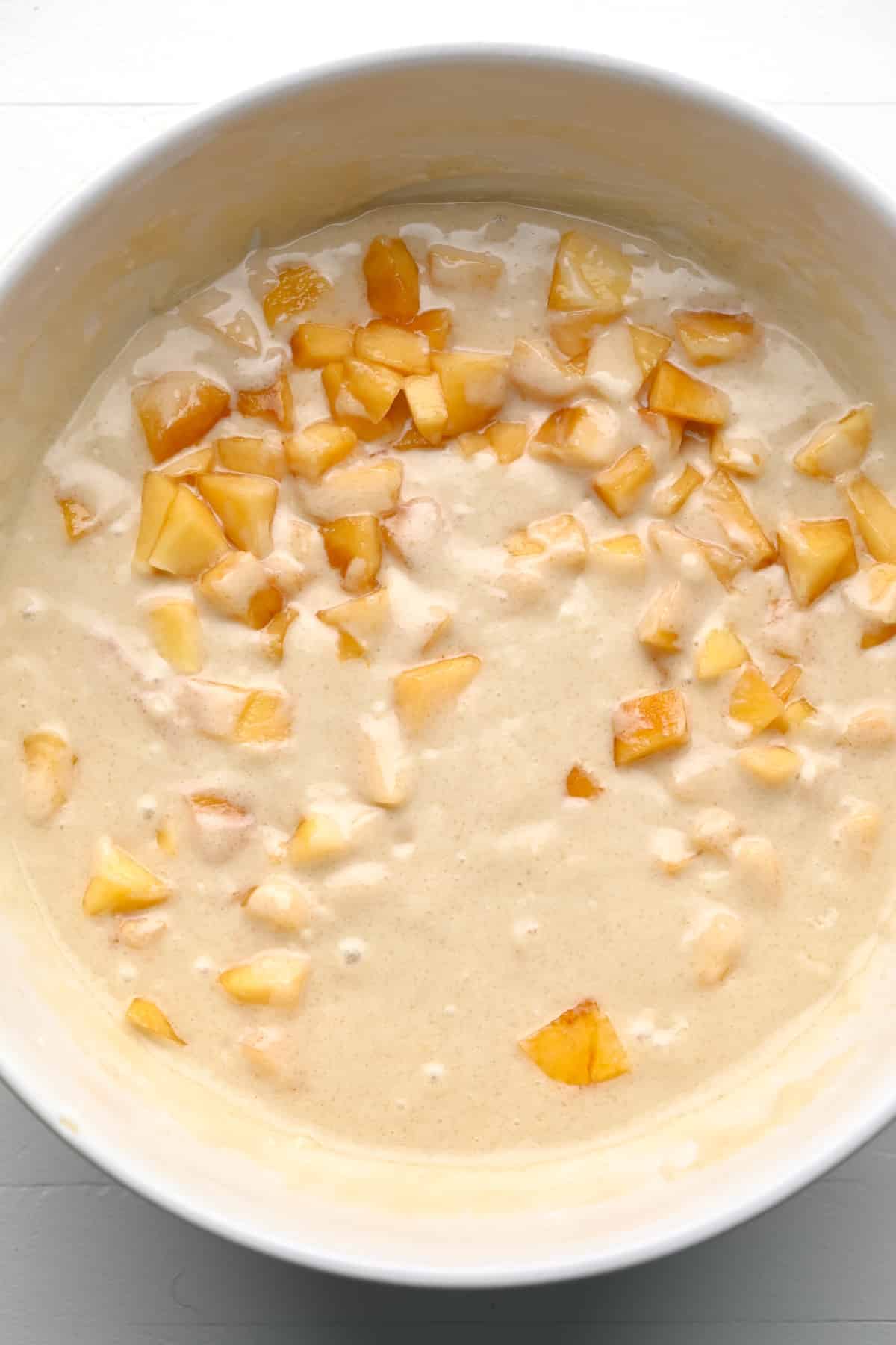 batter for cake with diced peaches throughout in a large bowl