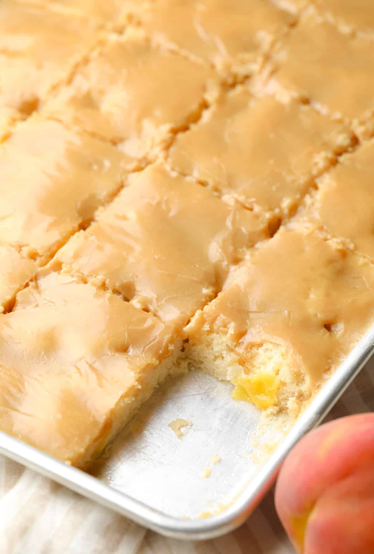 sheet pan with sliced peach cake with brown sugar frosting