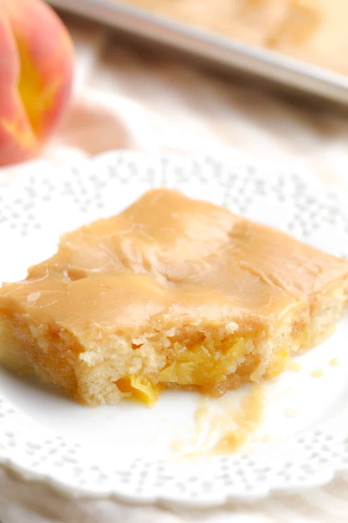 piece of cake on a white plate with a bite taken out of it showing peaches inside