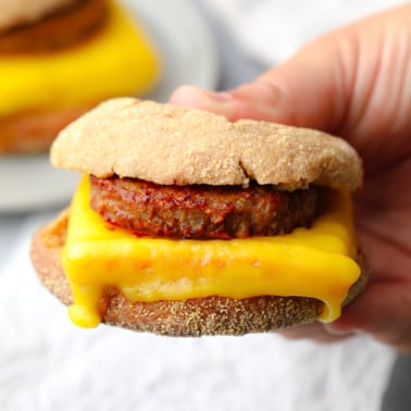 close up on a womans hand holding a vegan breakfast sandwich.