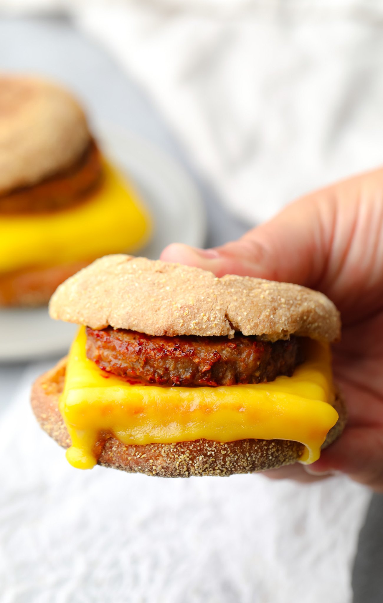 close up on a womans hand holding a vegan breakfast sandwich.