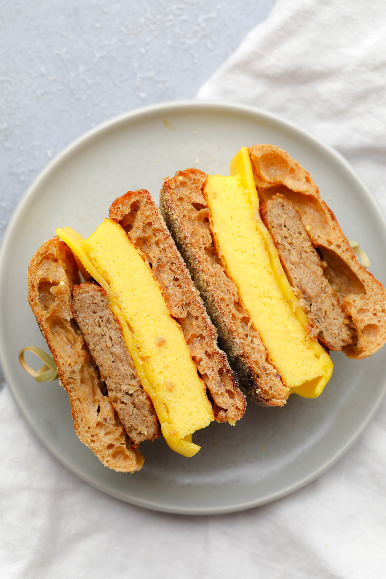 a vegan breakfast sandwich cut in half on a grey plate.