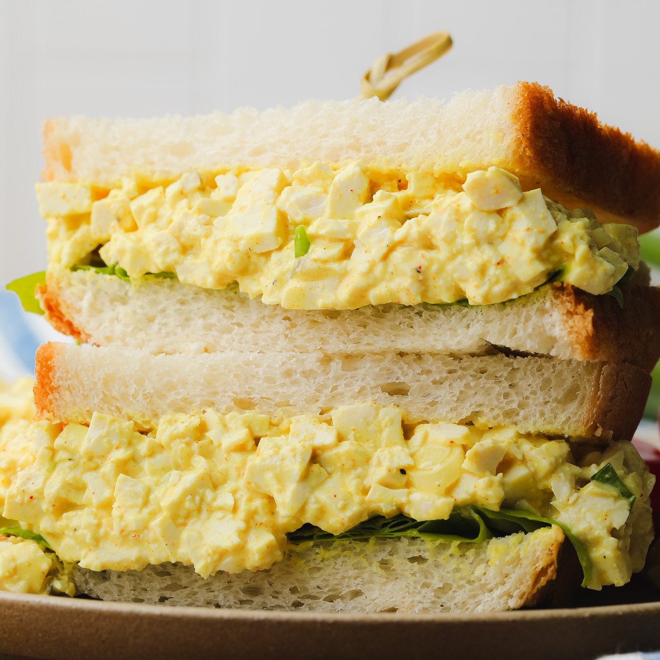 two vegan egg salad sandwiched piled on top of each other.