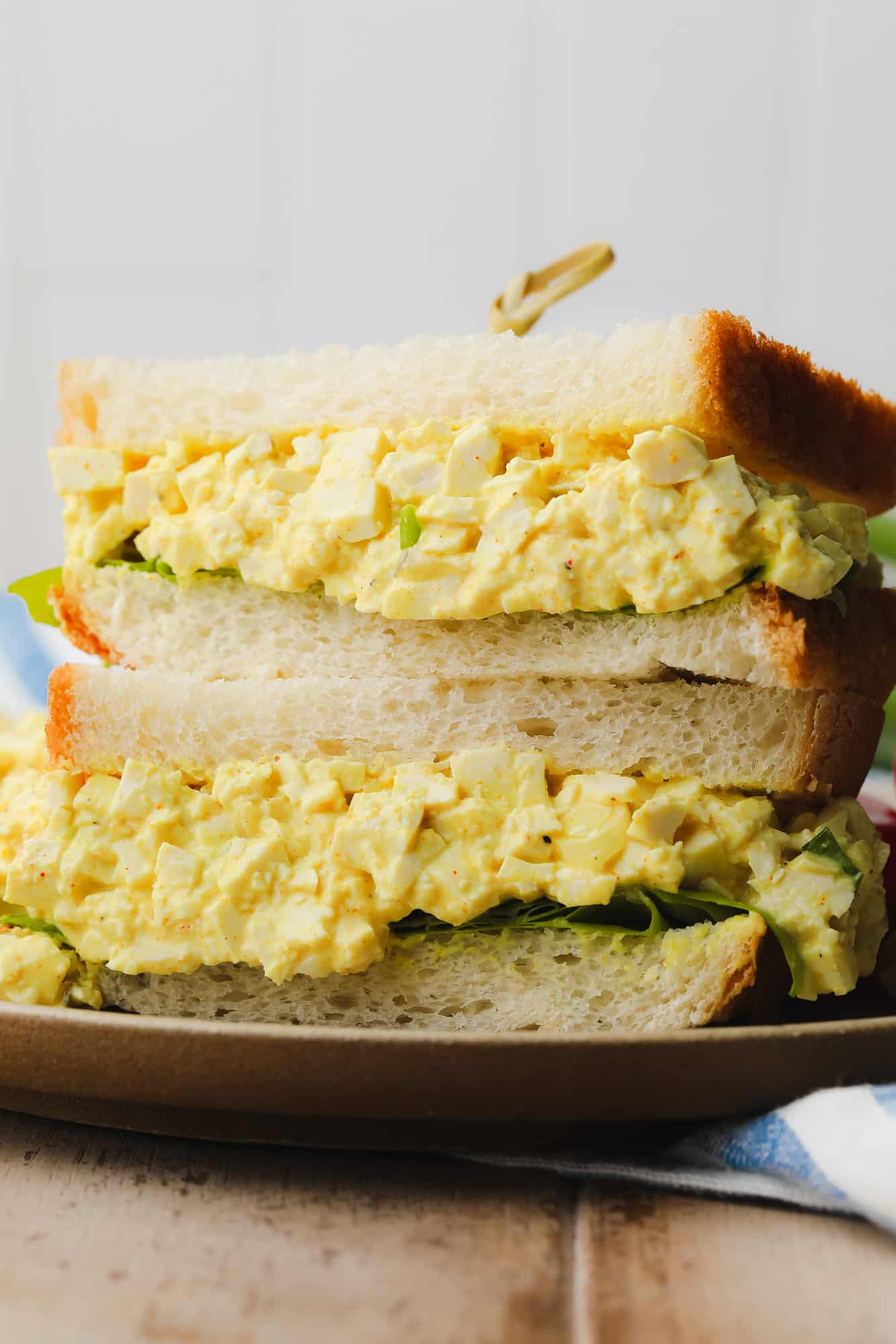 two vegan egg salad sandwiched piled on top of each other.