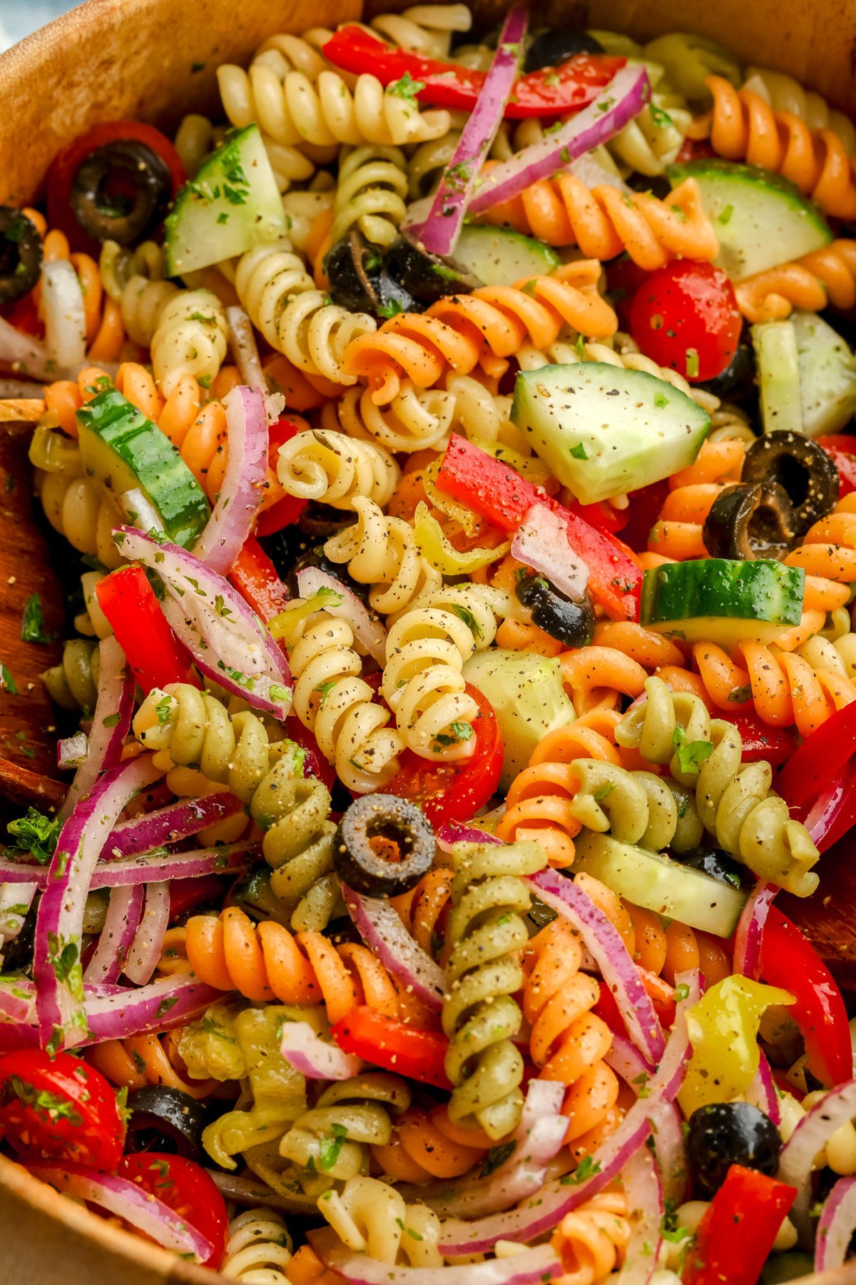 close up of rainbow noodles in a wood bowl with lots of vegetables