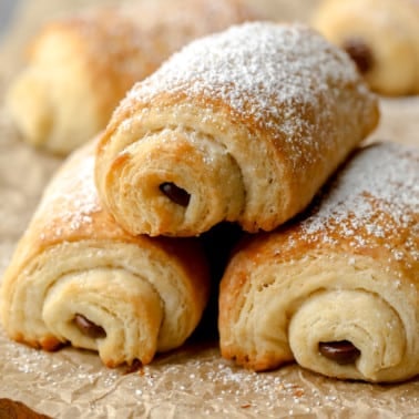 square image of stacked chocolate croissants with powdered sugar on top