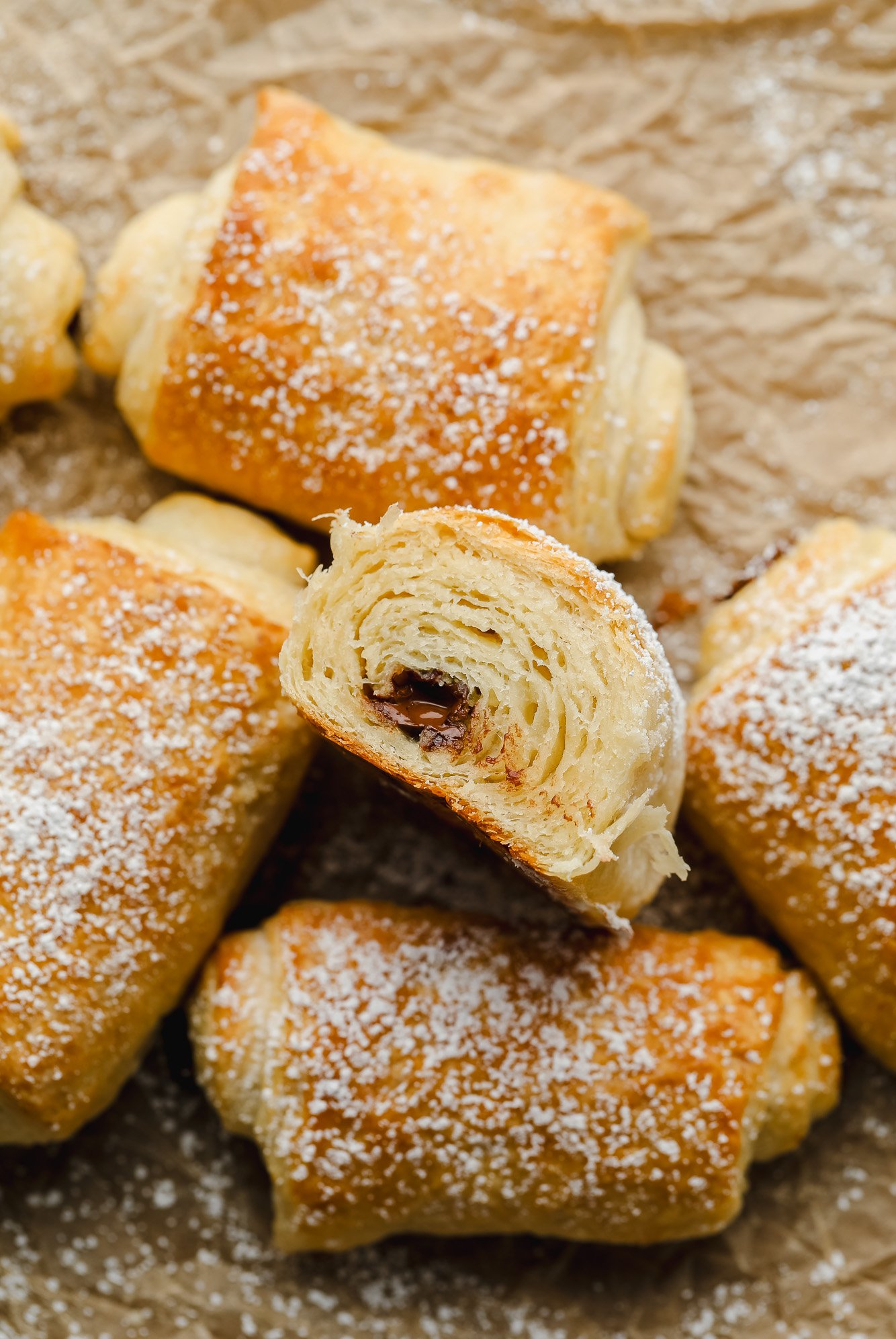 cut open vegan pain au chocolat showing flaky layers on parchment crinkle paper