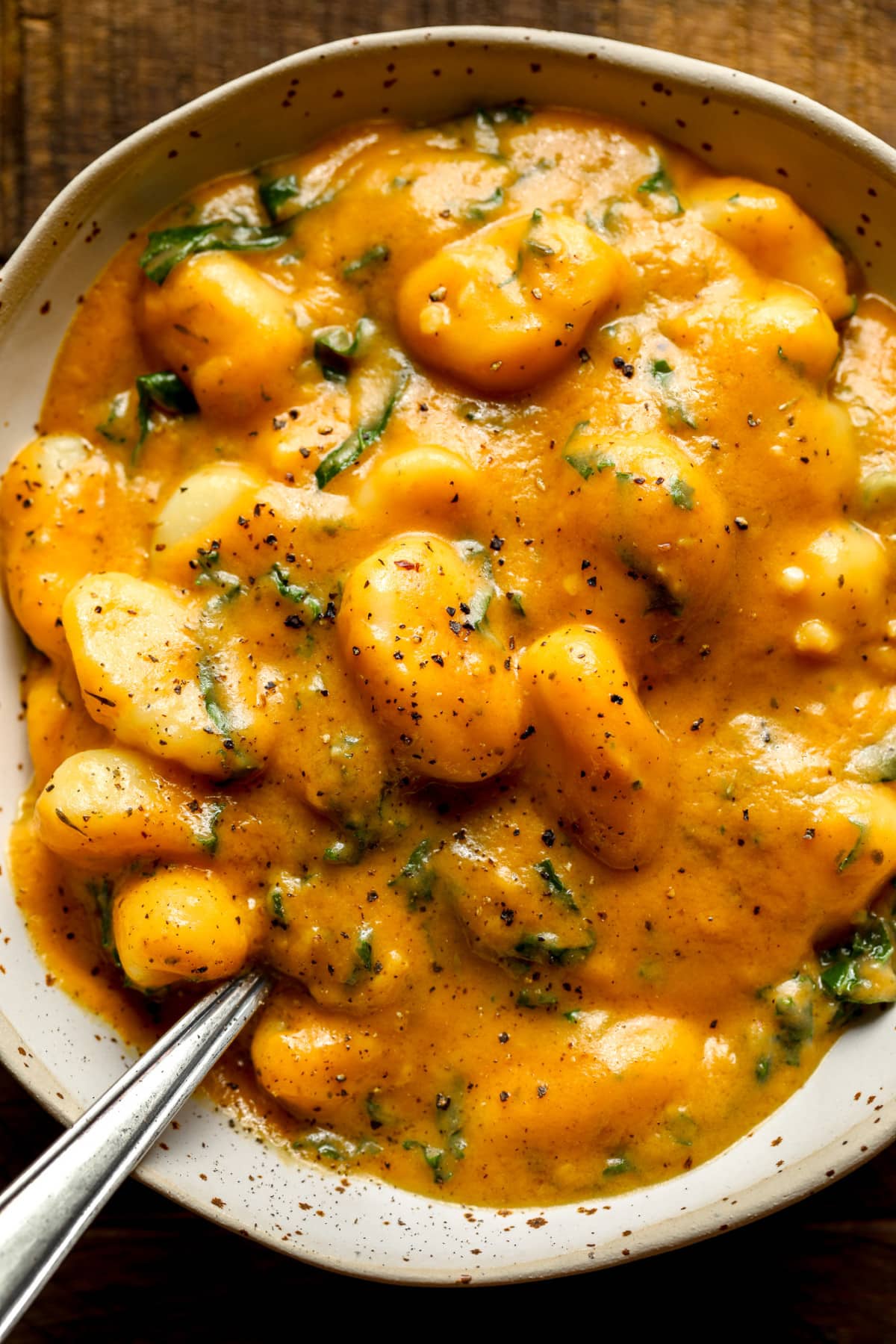 close up on a grey bowl filled with cooked pumpkin gnocchi.