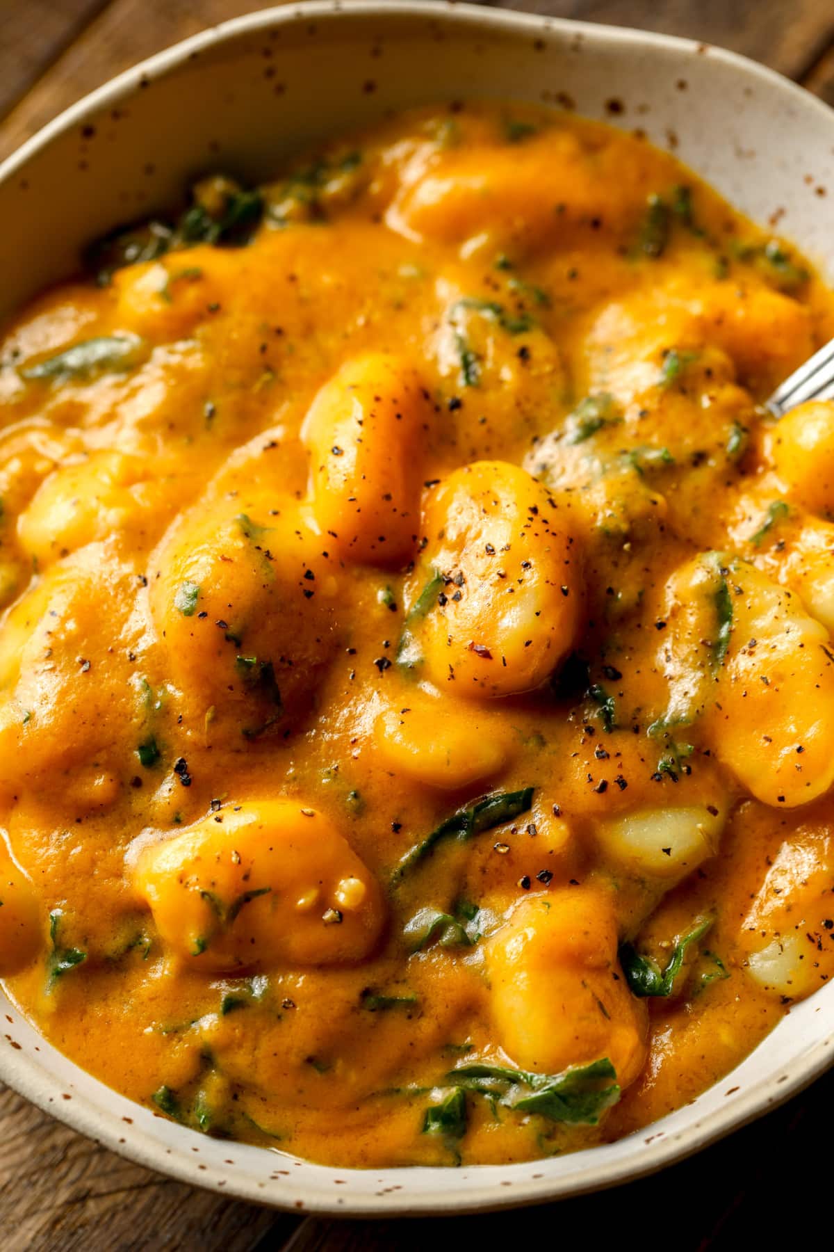 close up on a grey bowl filled with cooked pumpkin gnocchi.