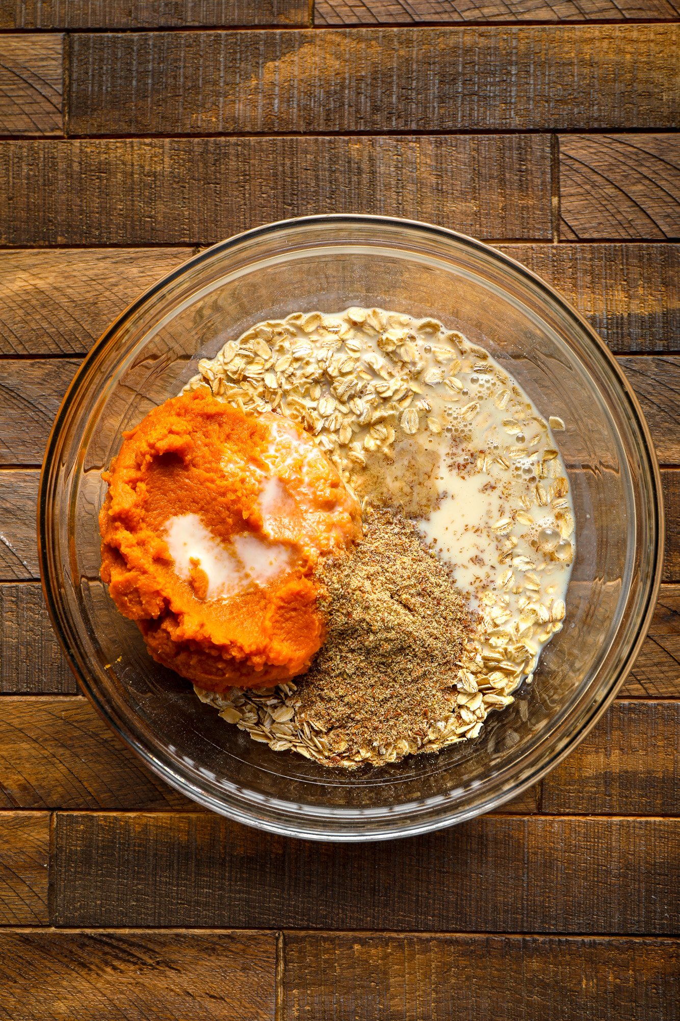 ingredients for pumpkin baked oatmeal together in a glass bowl.