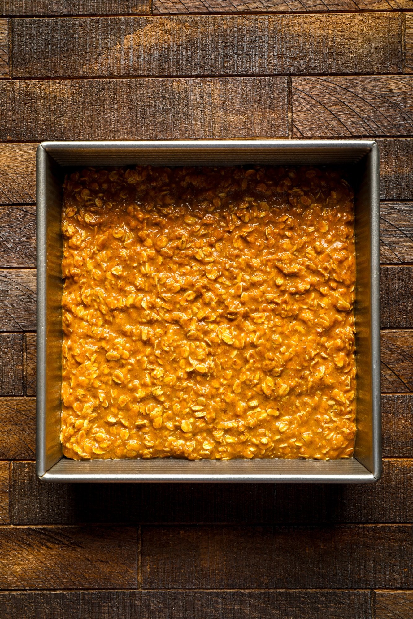 unbaked pumpkin oatmeal in a square metal baking pan.