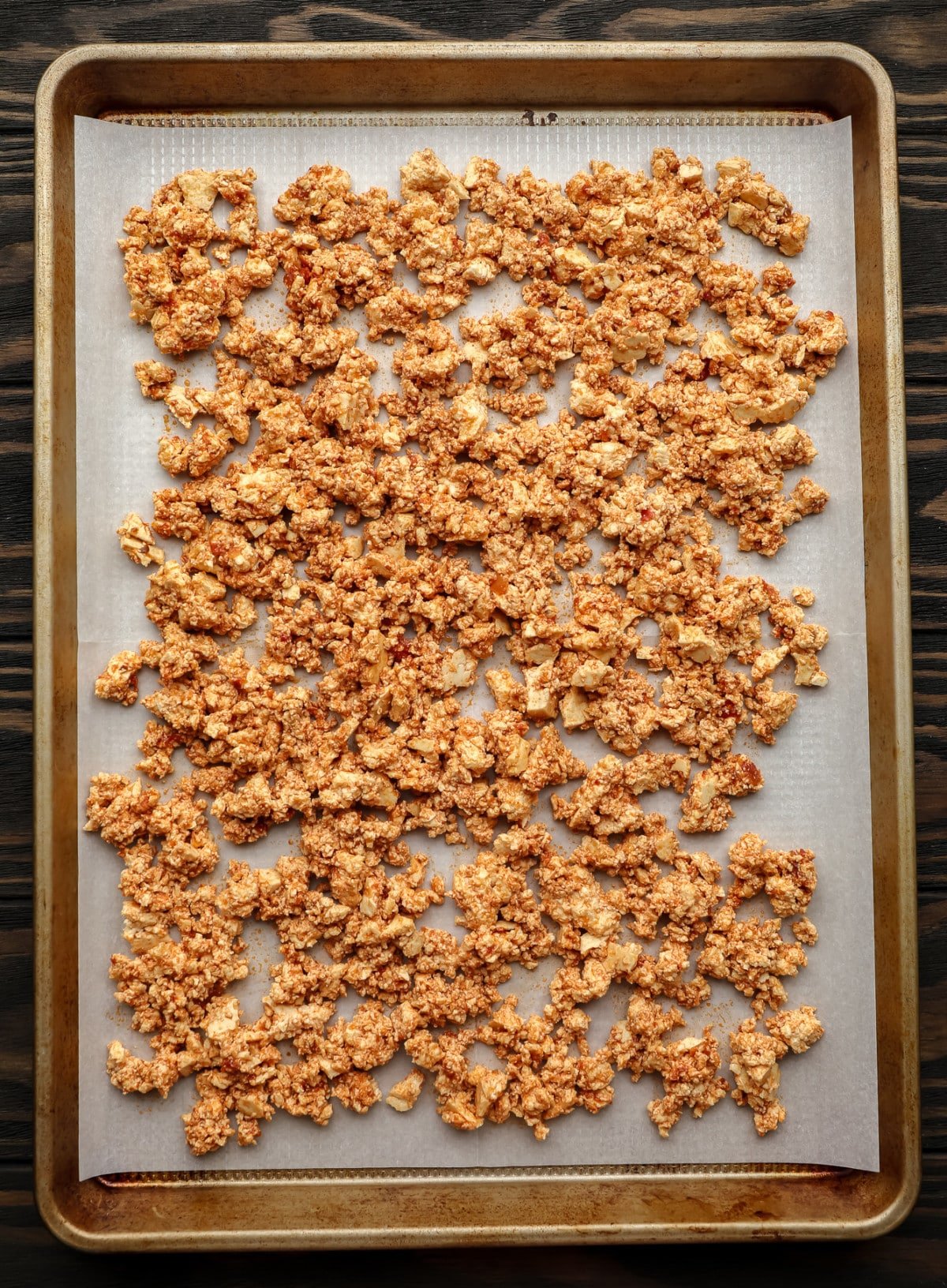 uncooked tofu crumbles on parchment lined gold pan