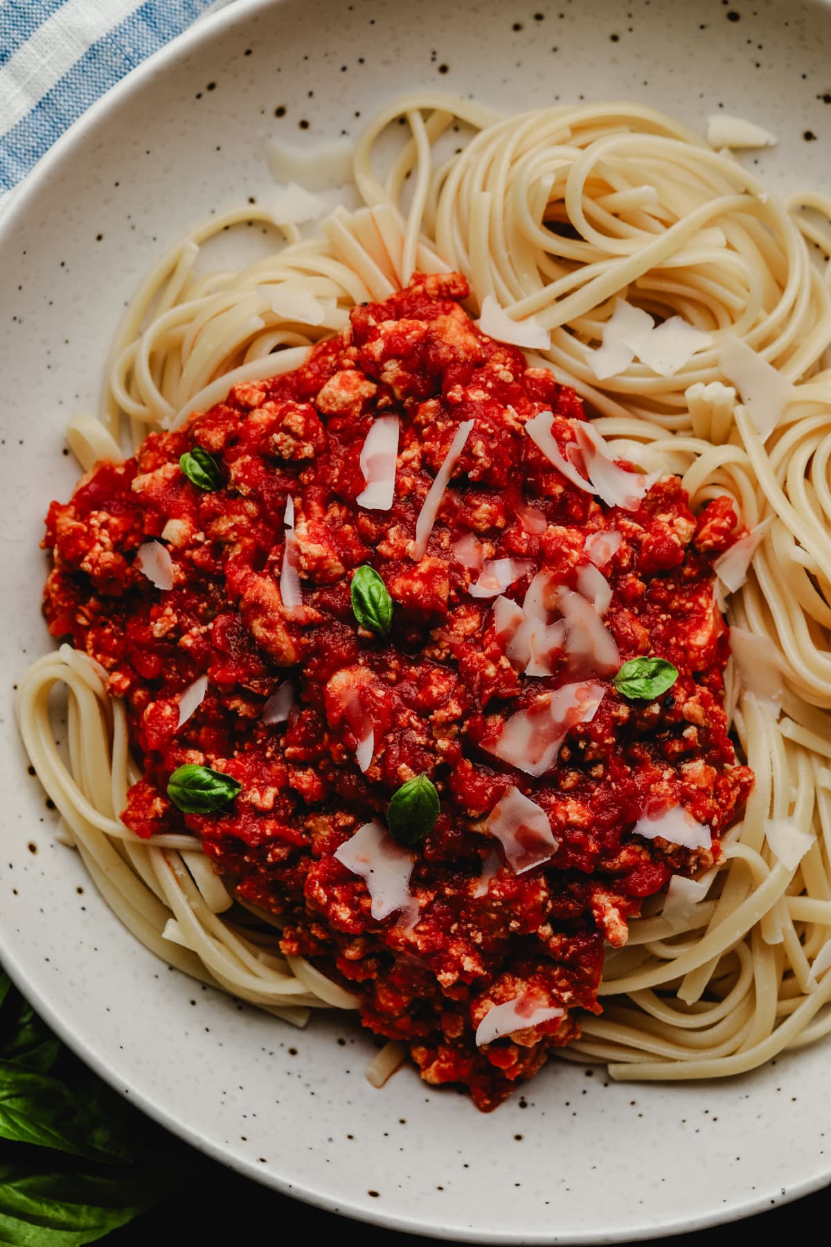 looking down at a bowl of pasta with red sauce with little pieces of tofu in it