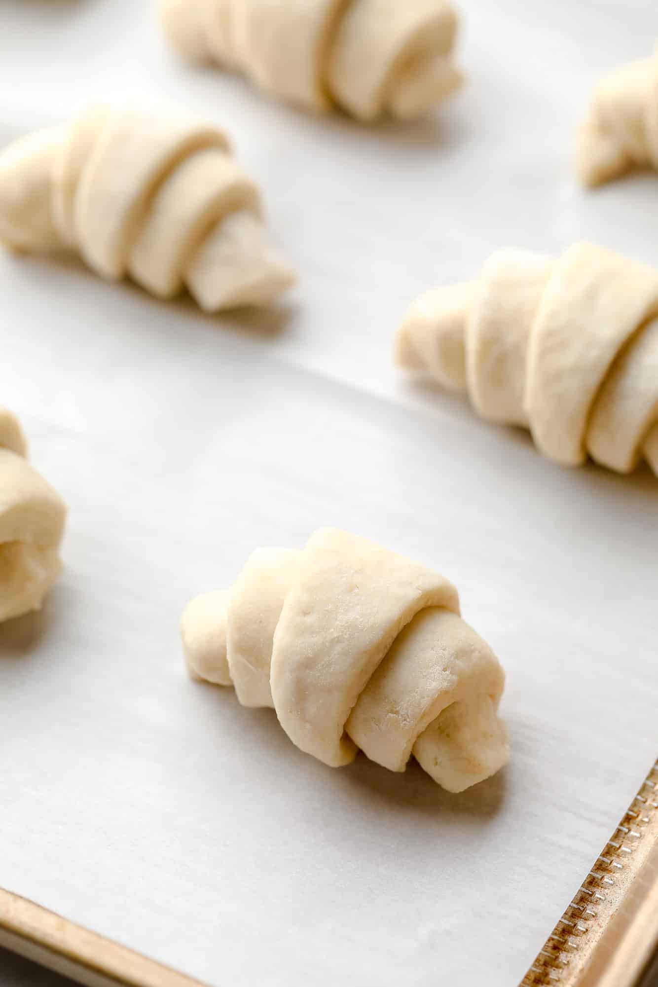 rolled crescent rolls on a parchment-lined baking sheet.