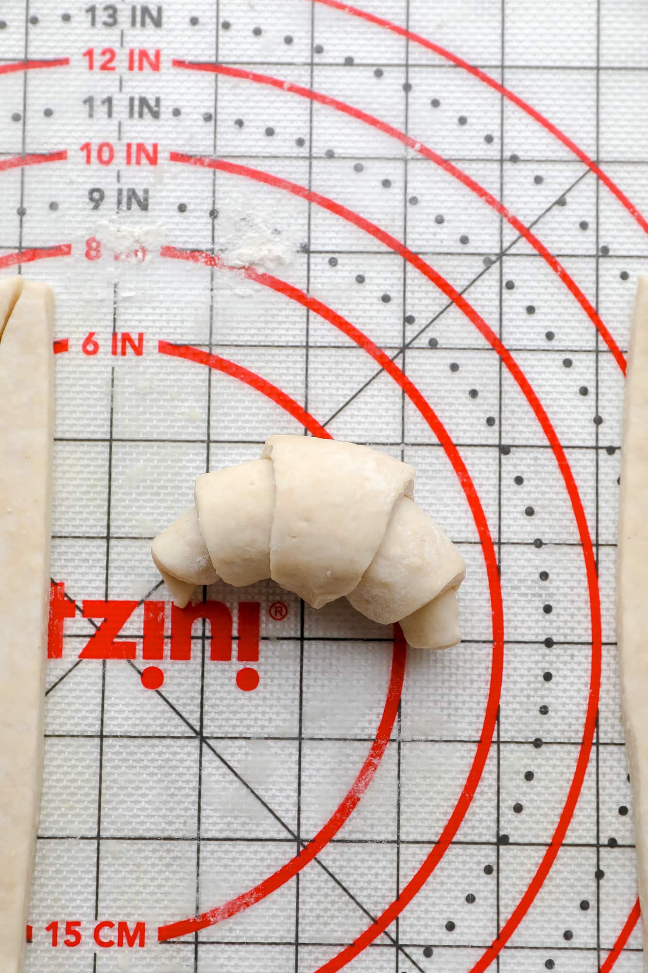 a rolled crescent roll on a pastry mat.