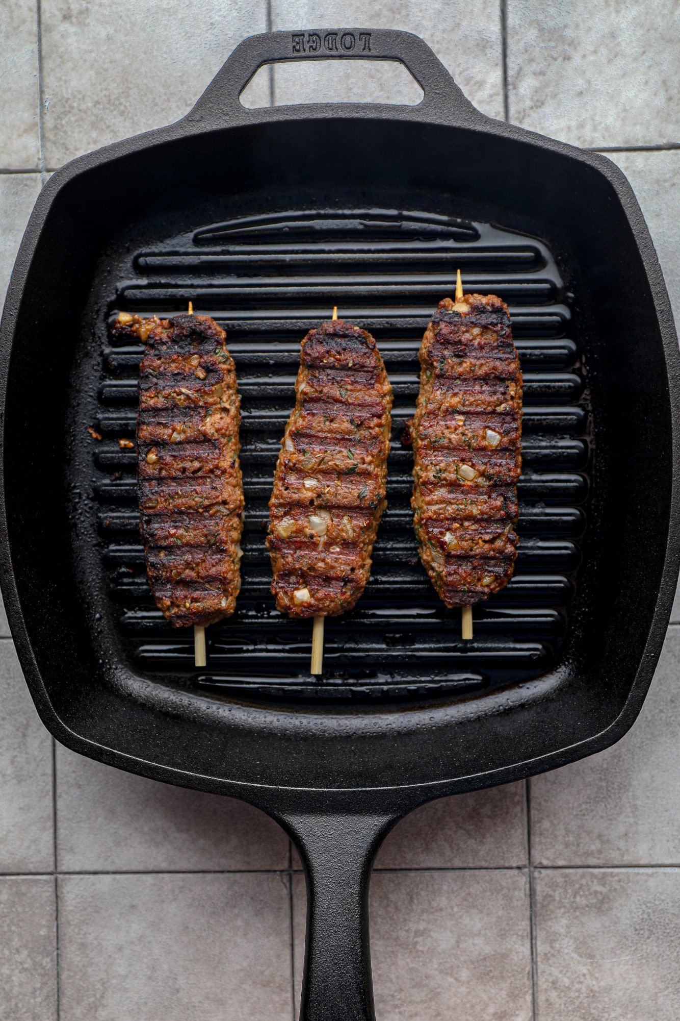 grilling 3 vegan kofta kebabs on a black grill pan.
