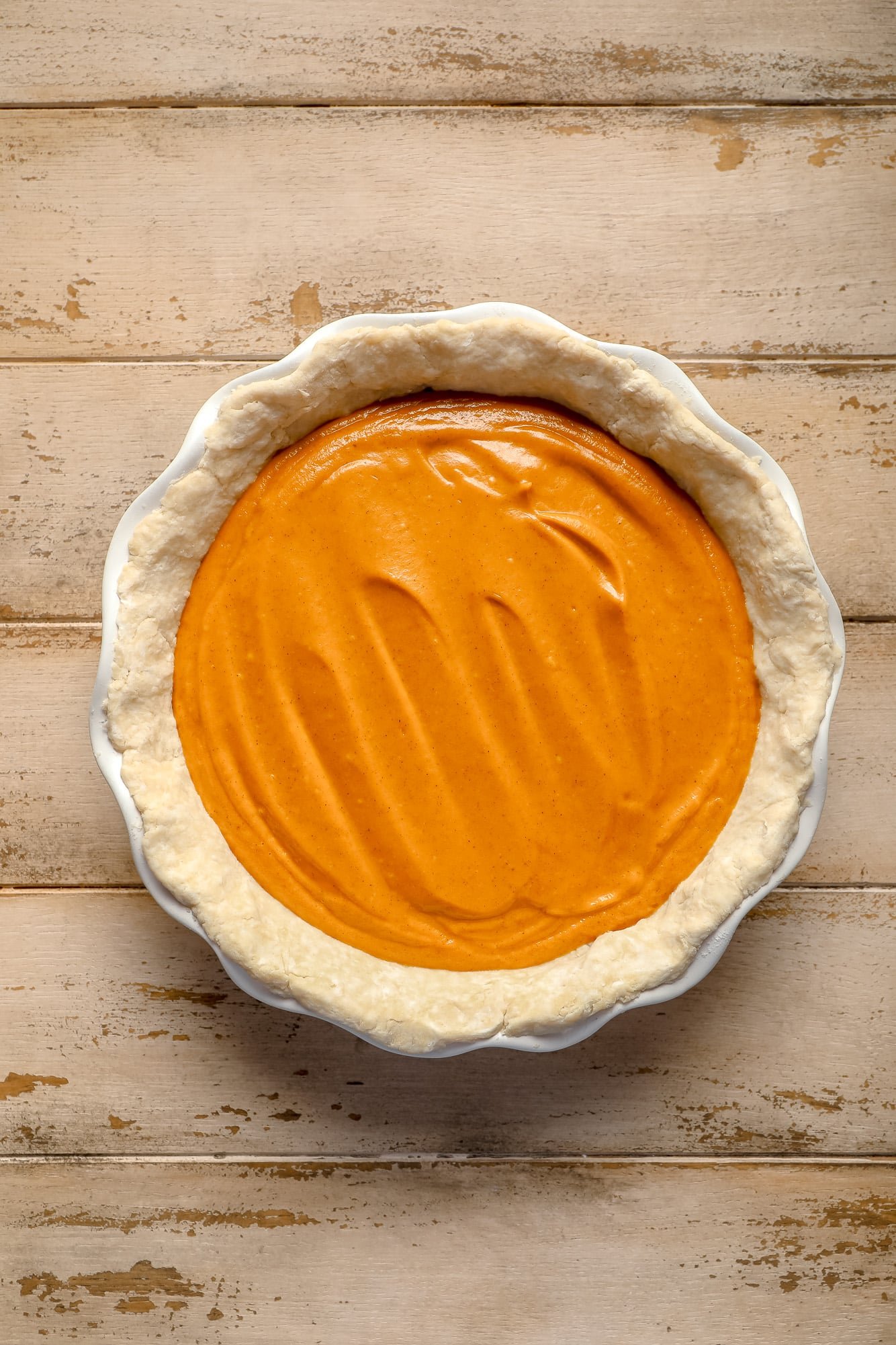 unbaked vegan pumpkin pie in a white pie dish.