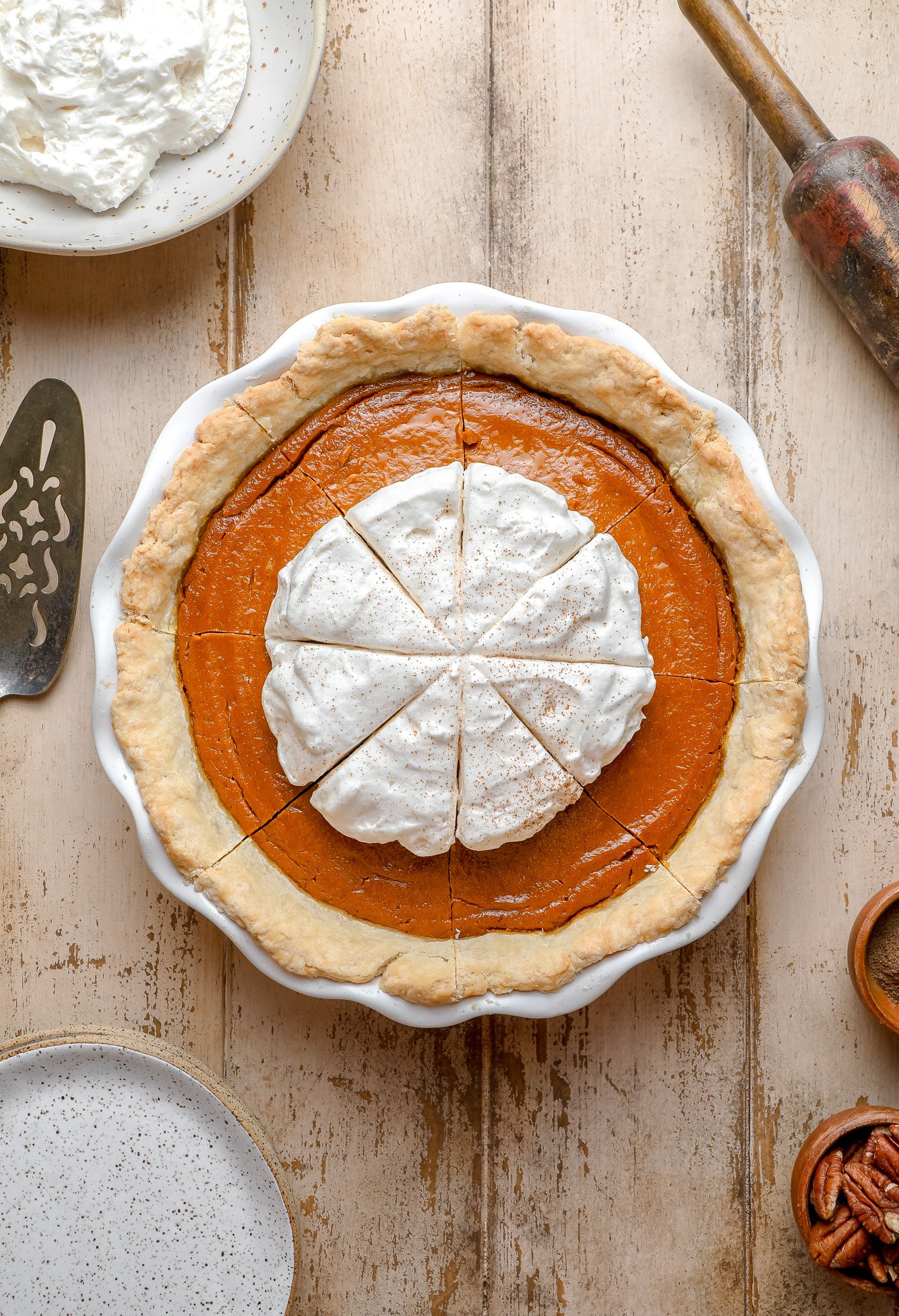 vegan pumpkin pie with whipped cream on top in a white pie dish.