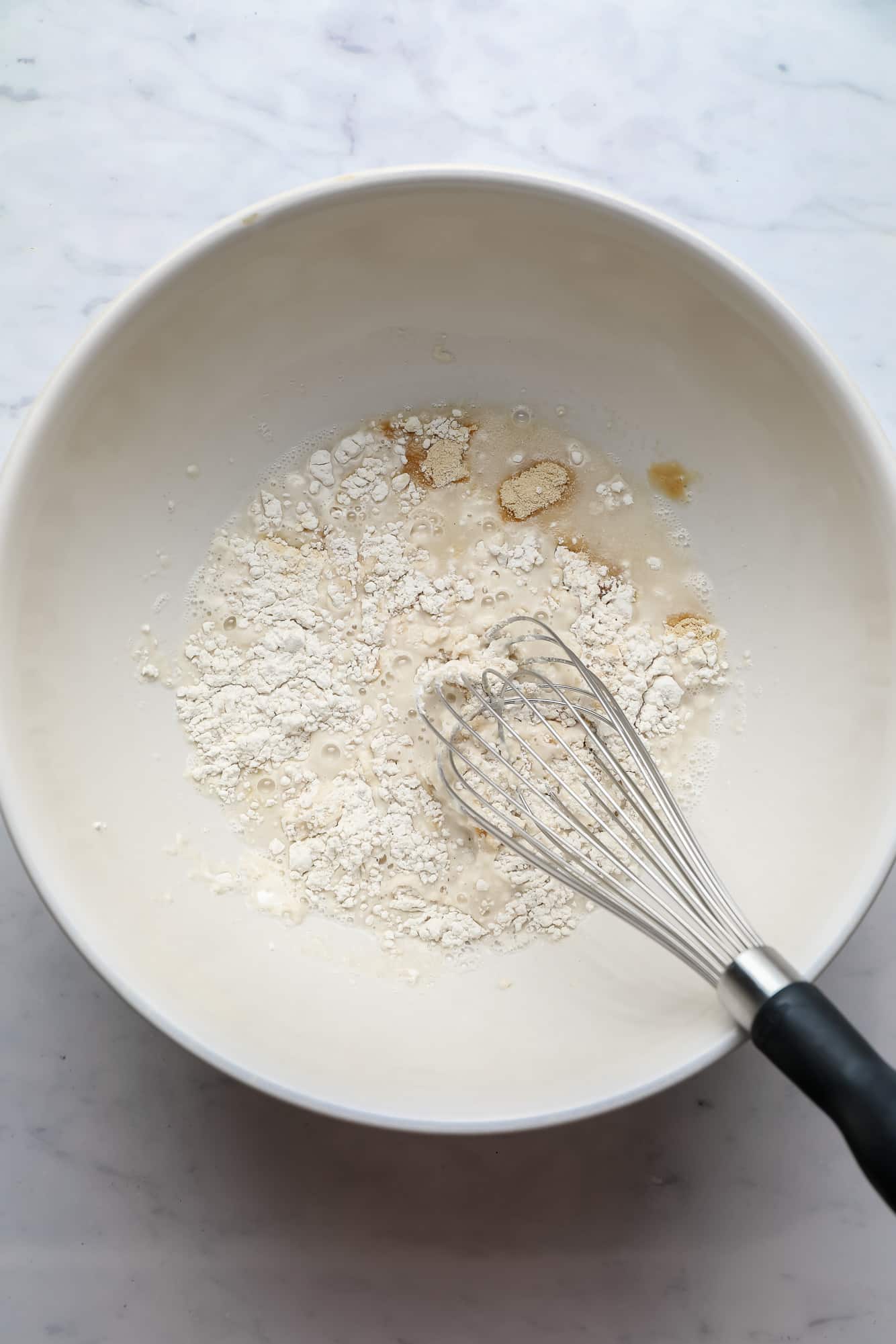 breading ingredients for cauliflower wings being whisked together in a large white bowl.