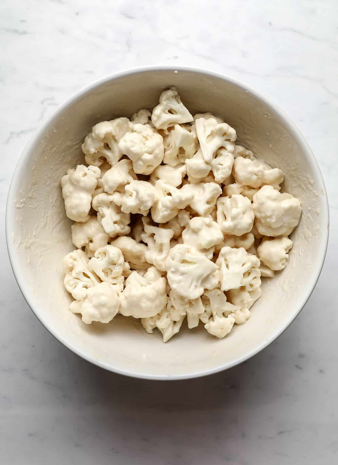 breaded cauliflower florets in a large white bowl.