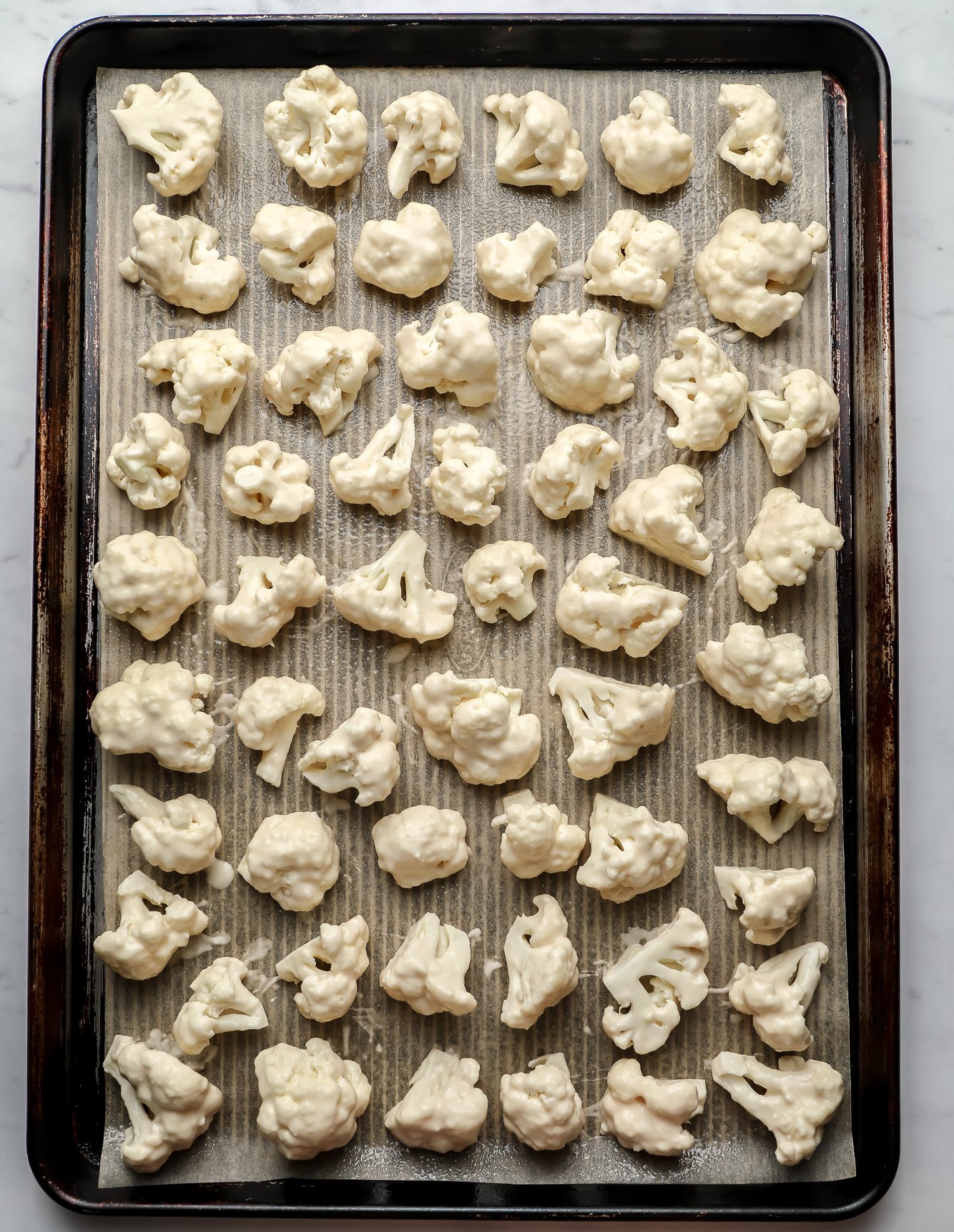 breaded cauliflower in rows on a baking sheet.