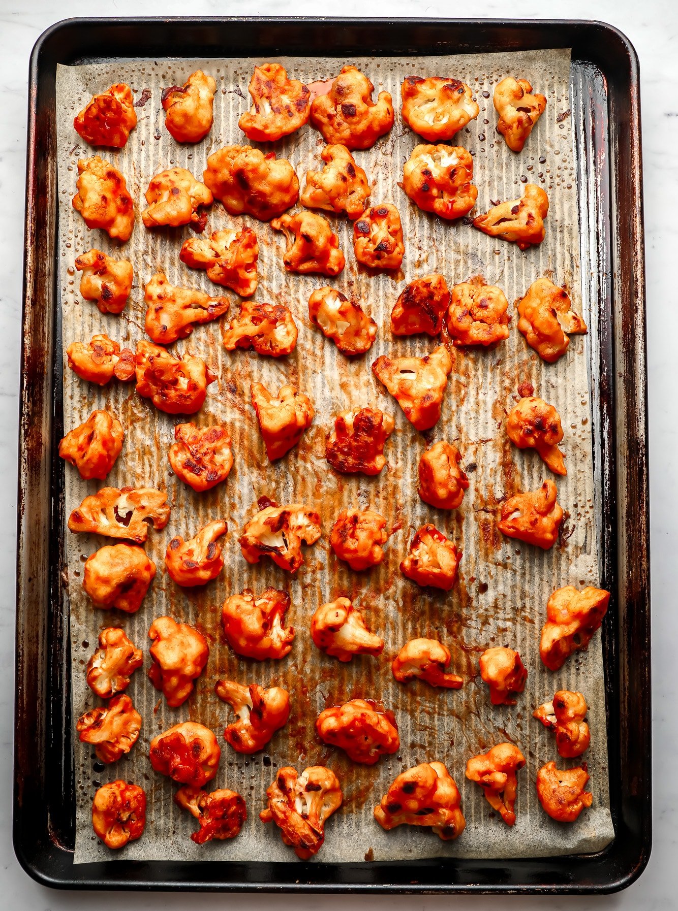 baked buffalo cauliflower wings in rows on a baking sheet.