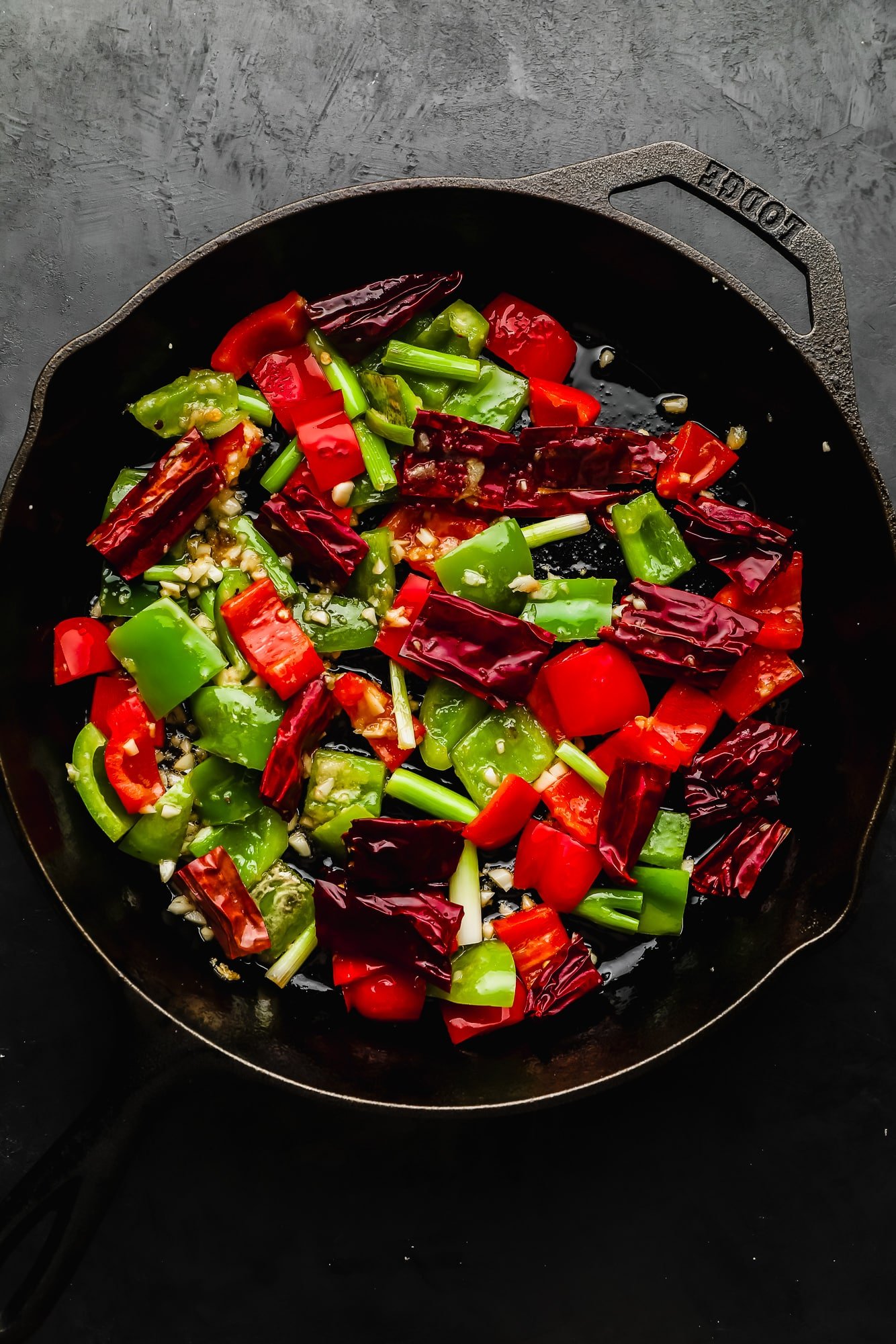 stir fried bell peppers and dried chili peppers in a black skillet.