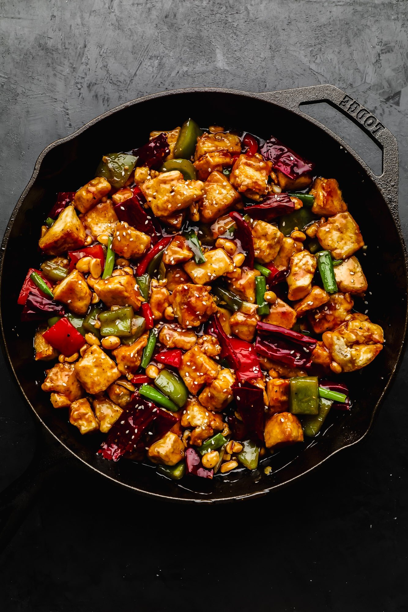 cooked kung pao tofu and vegetables in a large black cast iron skillet.